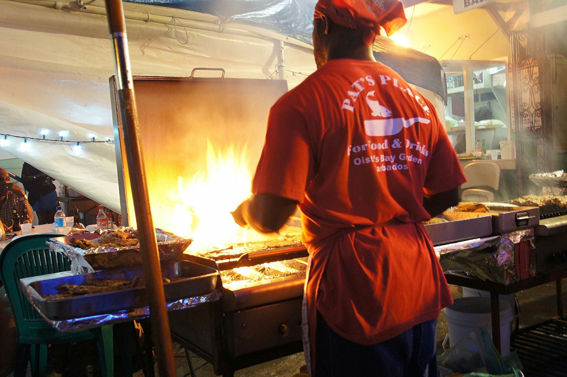 A local cooks up some fish in Oistins. Image by Dan Costin / CC by 