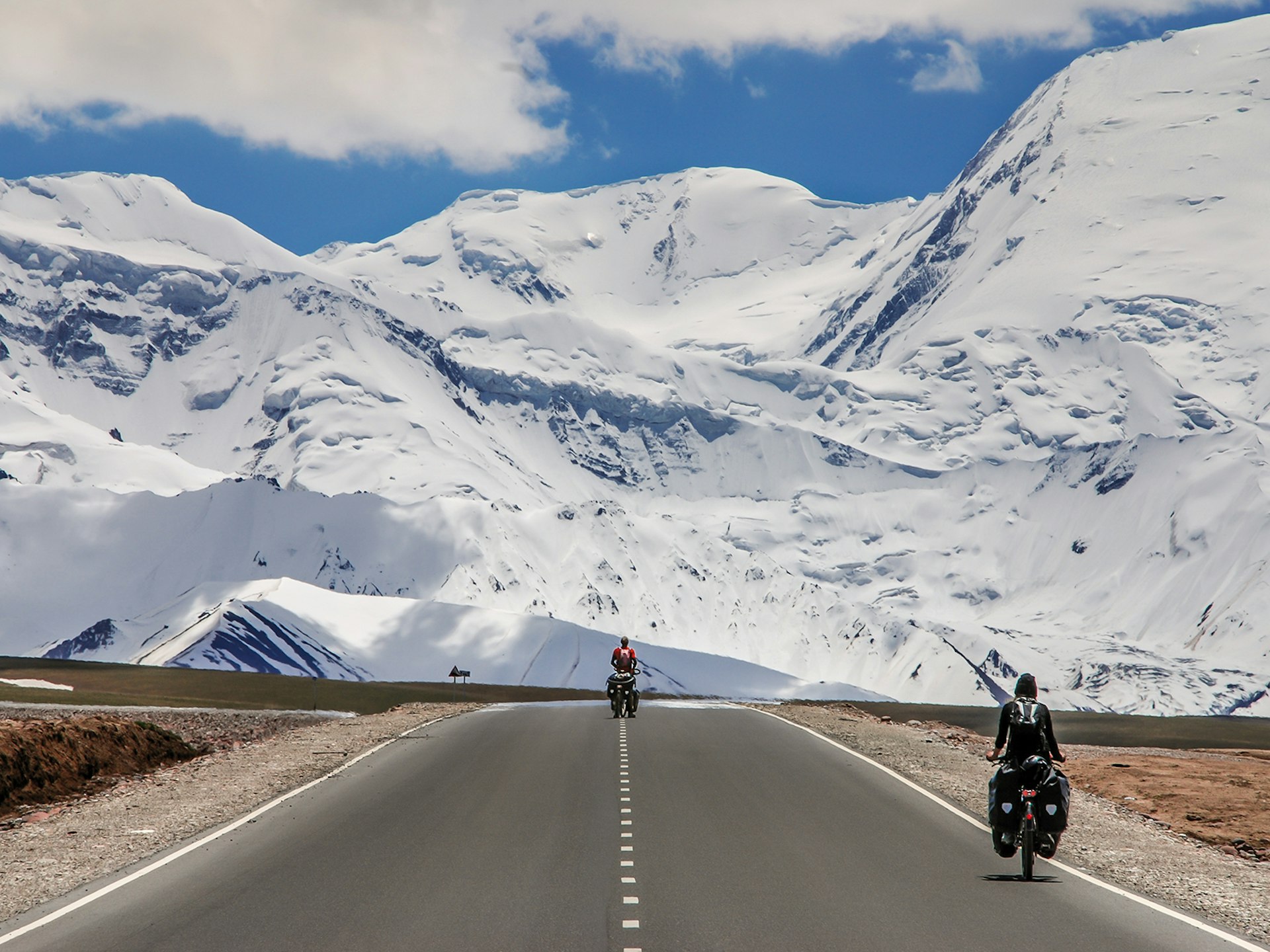Two cyclists approaching the Pamir Alay Mountains