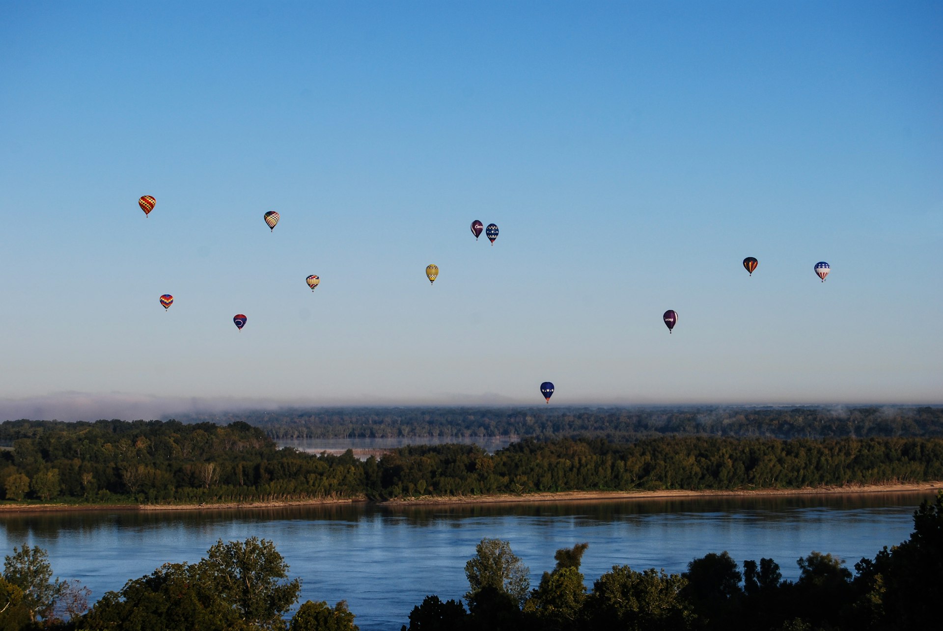 Hot air balloons float over the Mississippi River.