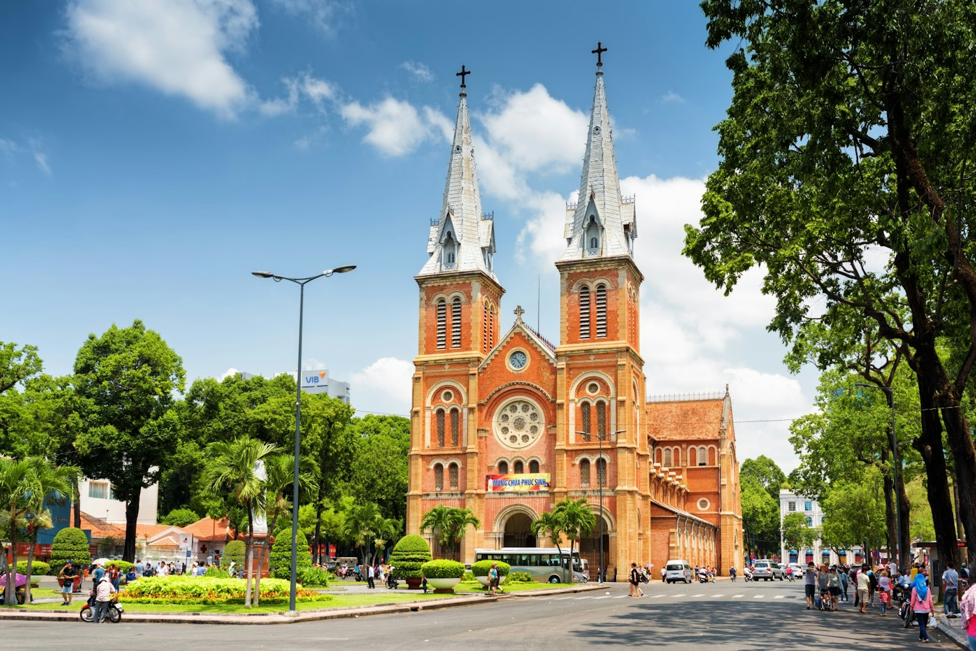 HCMC's Notre Dame Cathedral and the leafy surrounding square and street on a sunny, clear day © Efired / Shutterstock