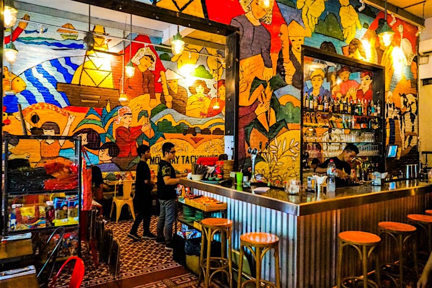 The interior of cafe-bar Propaganda Bistro, its walls completely covered in brightly coloured murals in the style of old propaganda art