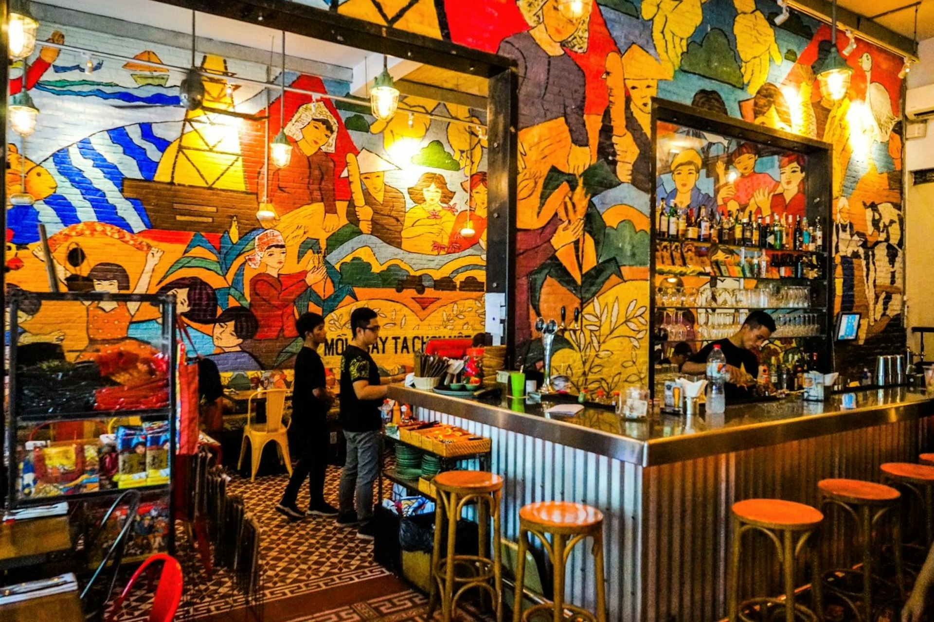 The interior of cafe-bar Propaganda Bistro, its walls completely covered in brightly coloured murals in the style of old propaganda art