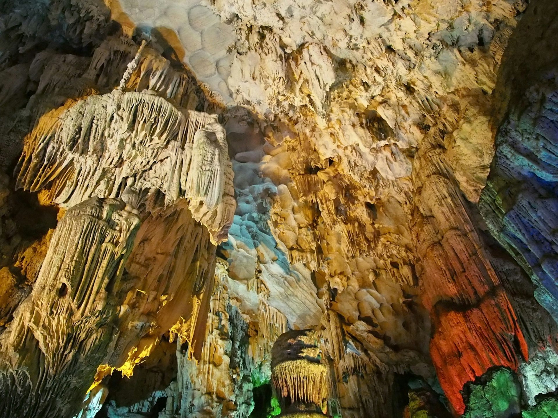 Tan stalactites and stalagmites are illuminated by red, green and yellow lights inside Hang Thien Cung, a cave at Halong Bay.