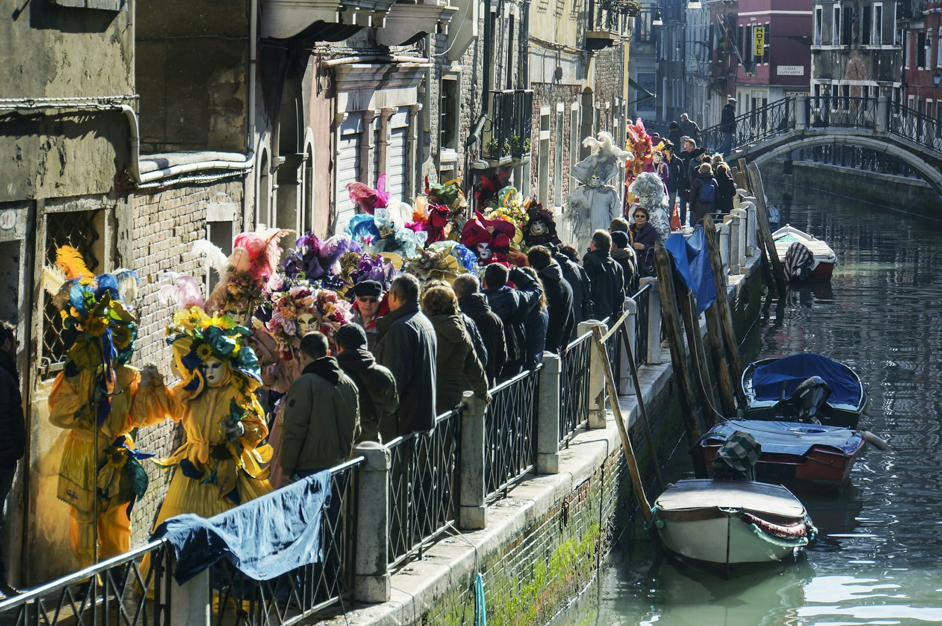 A procession of masked revellers making their way down a canal in Venice 