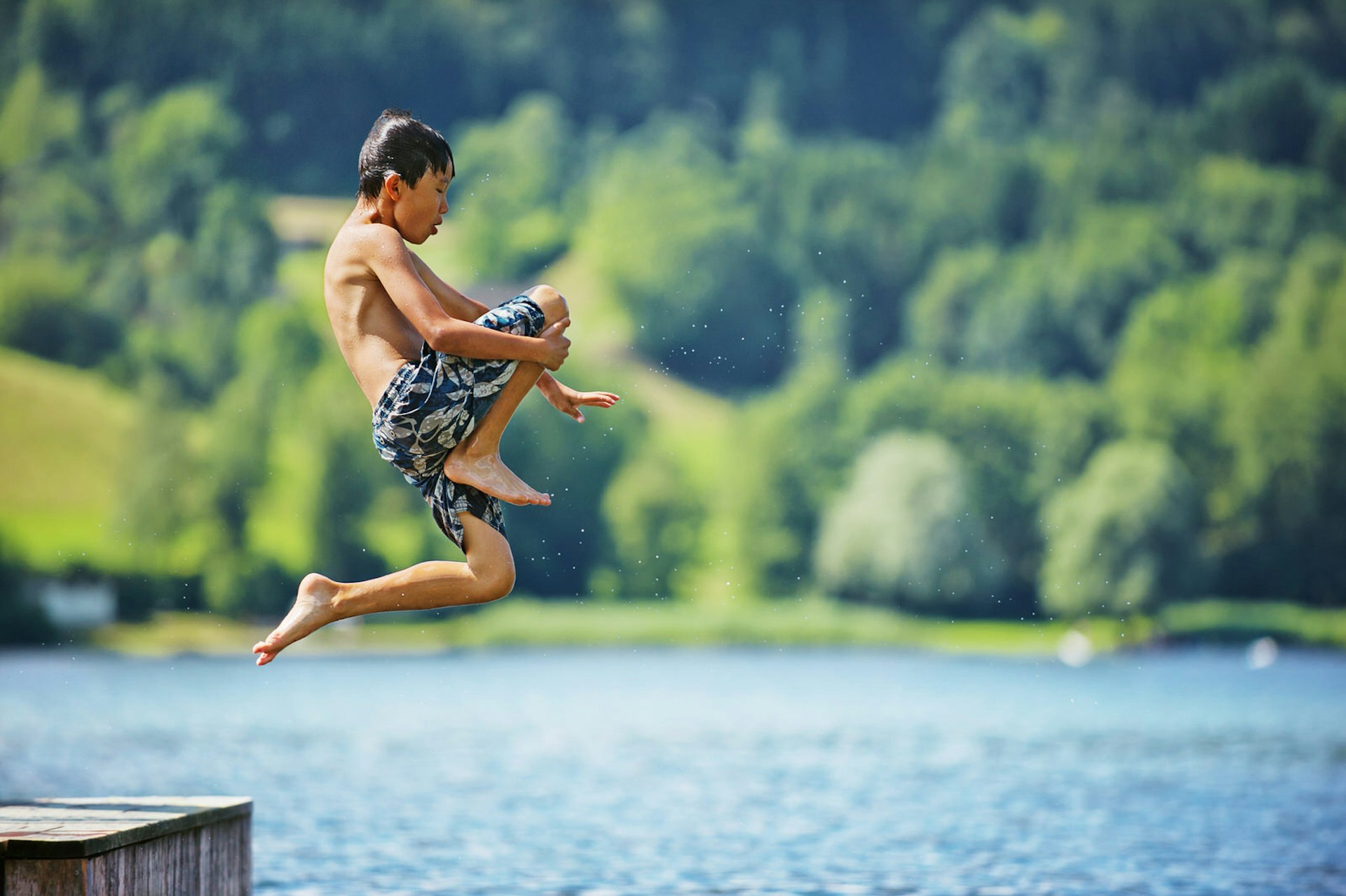 Asian boy jumping in lake