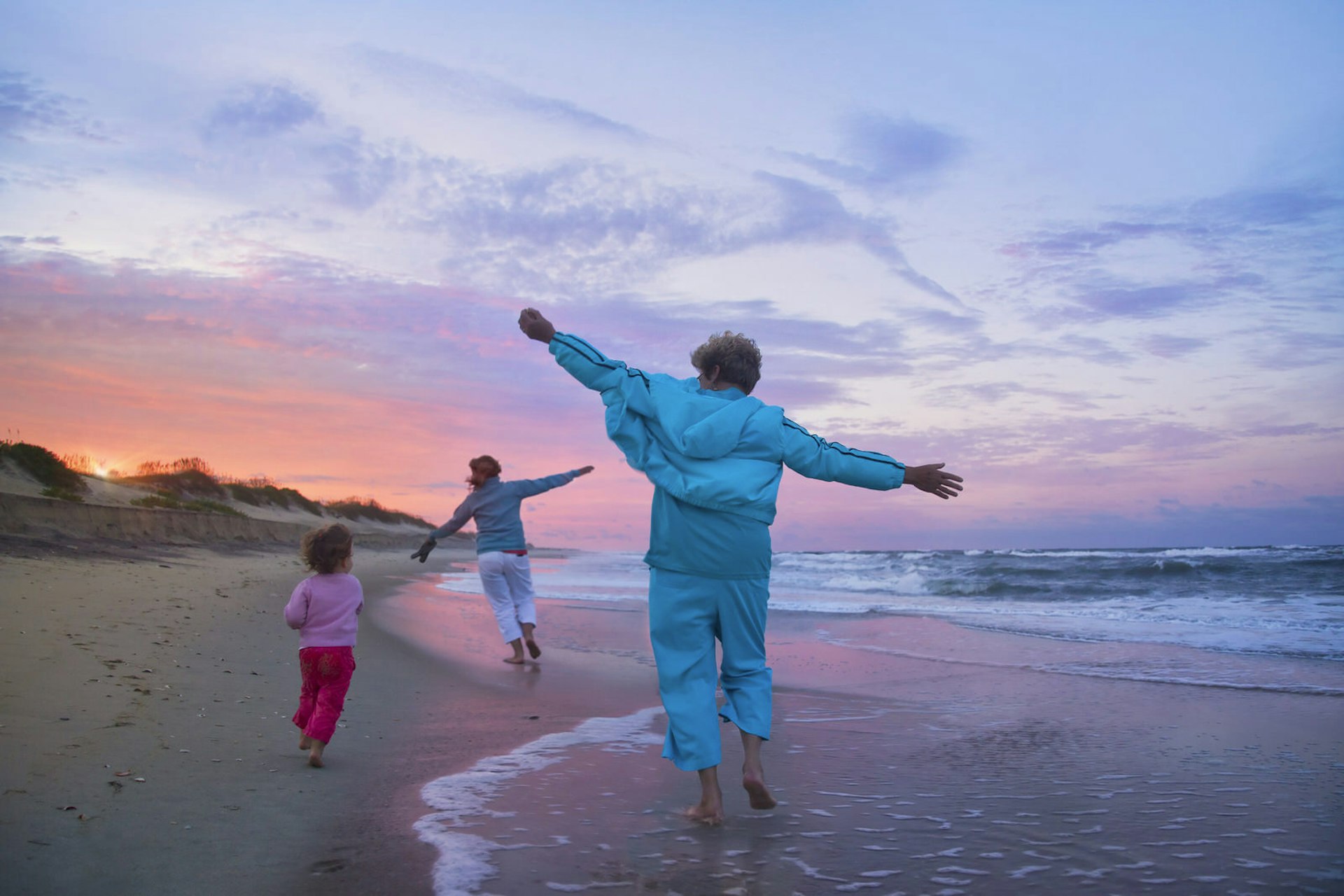 Mother, child, and grandmother running on a beach
