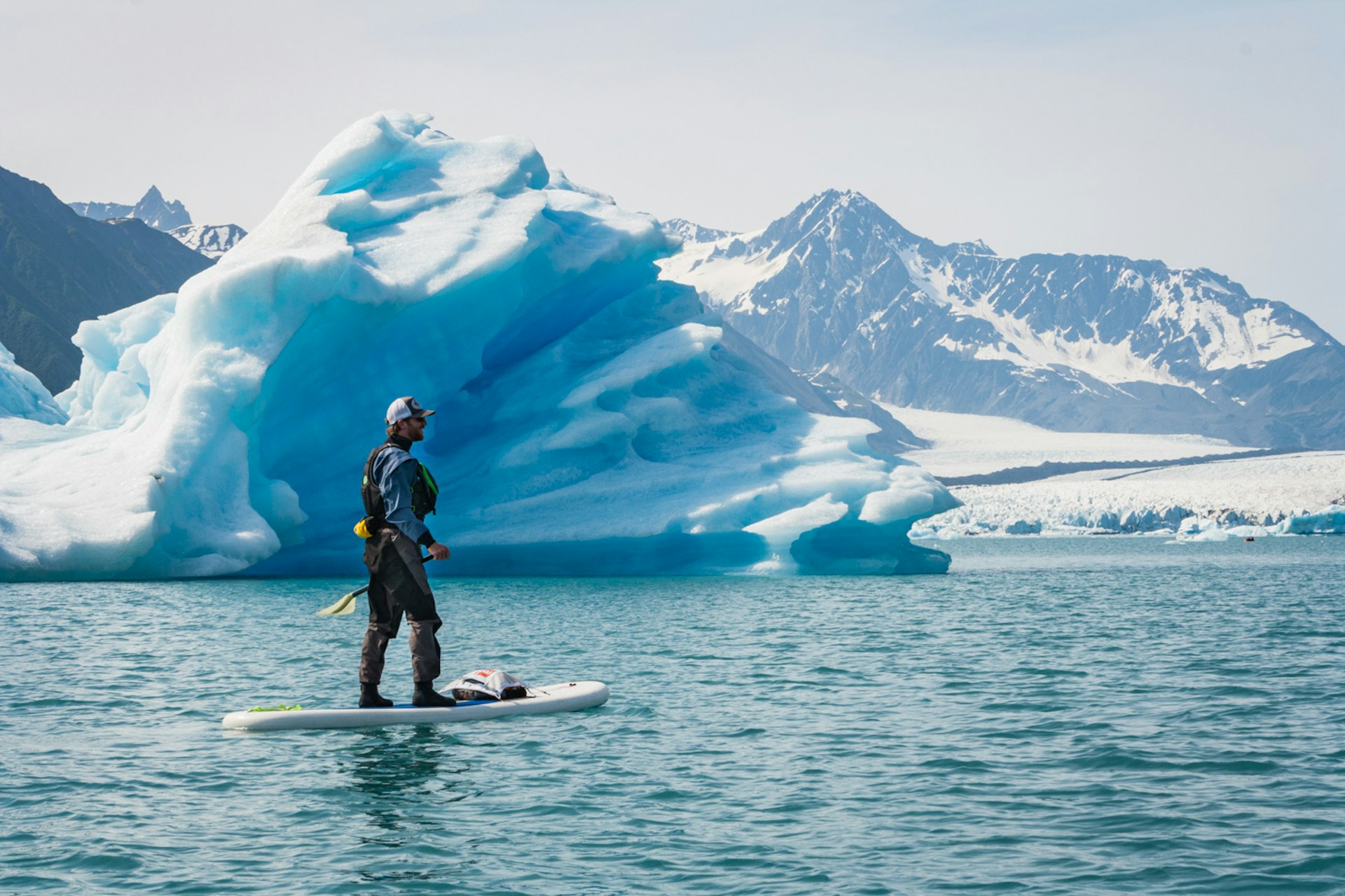 A paddleboarder glides past an iceberg © Alexander Howard / Lonely Planet