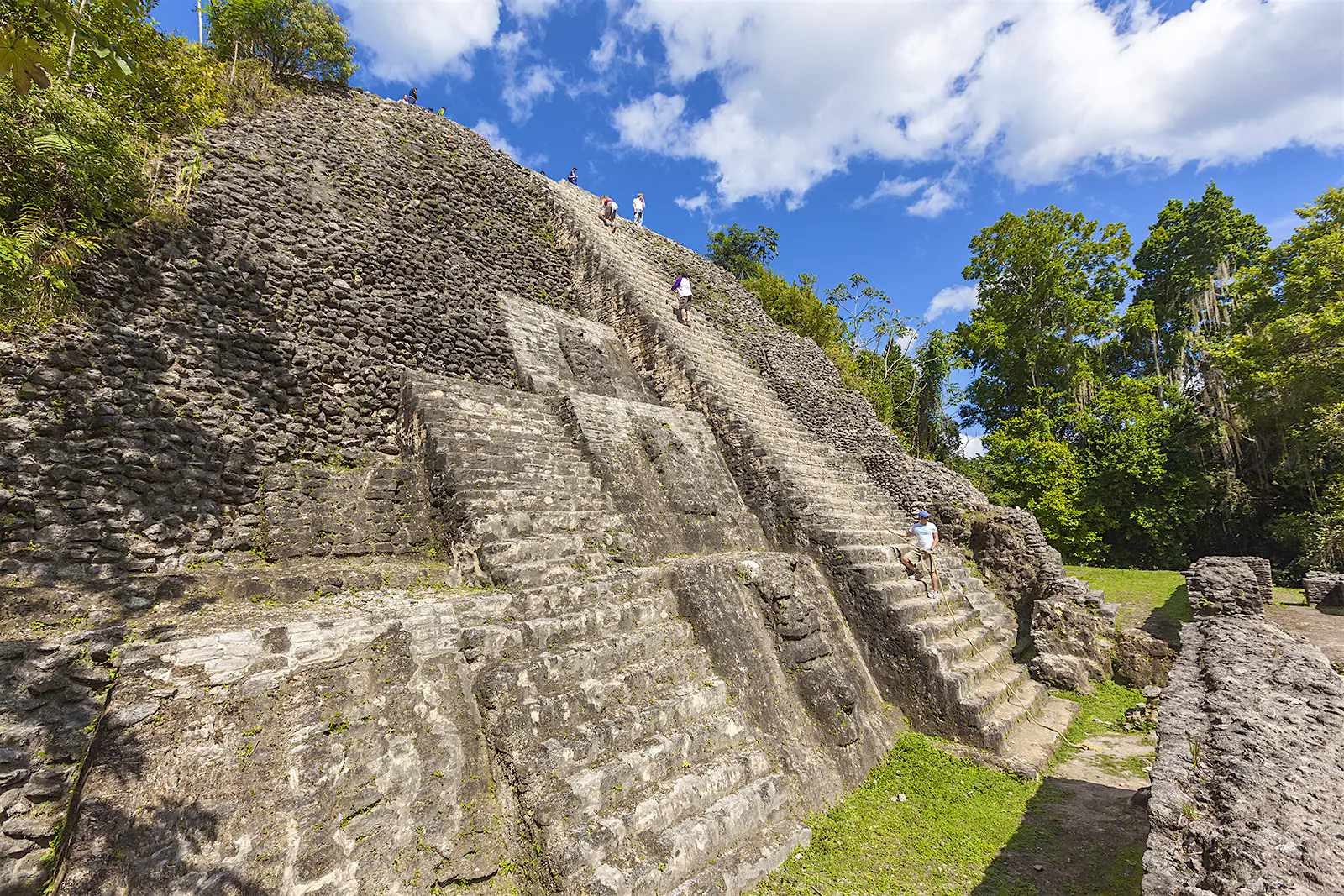 Features - Ancient Mayan ruins of Lamanai, Belize Visitors climb to the top of the Maya ruins in Lamanai, Belize © Patrick J Endres - AlaskaPhotoGraphics / Getty Images