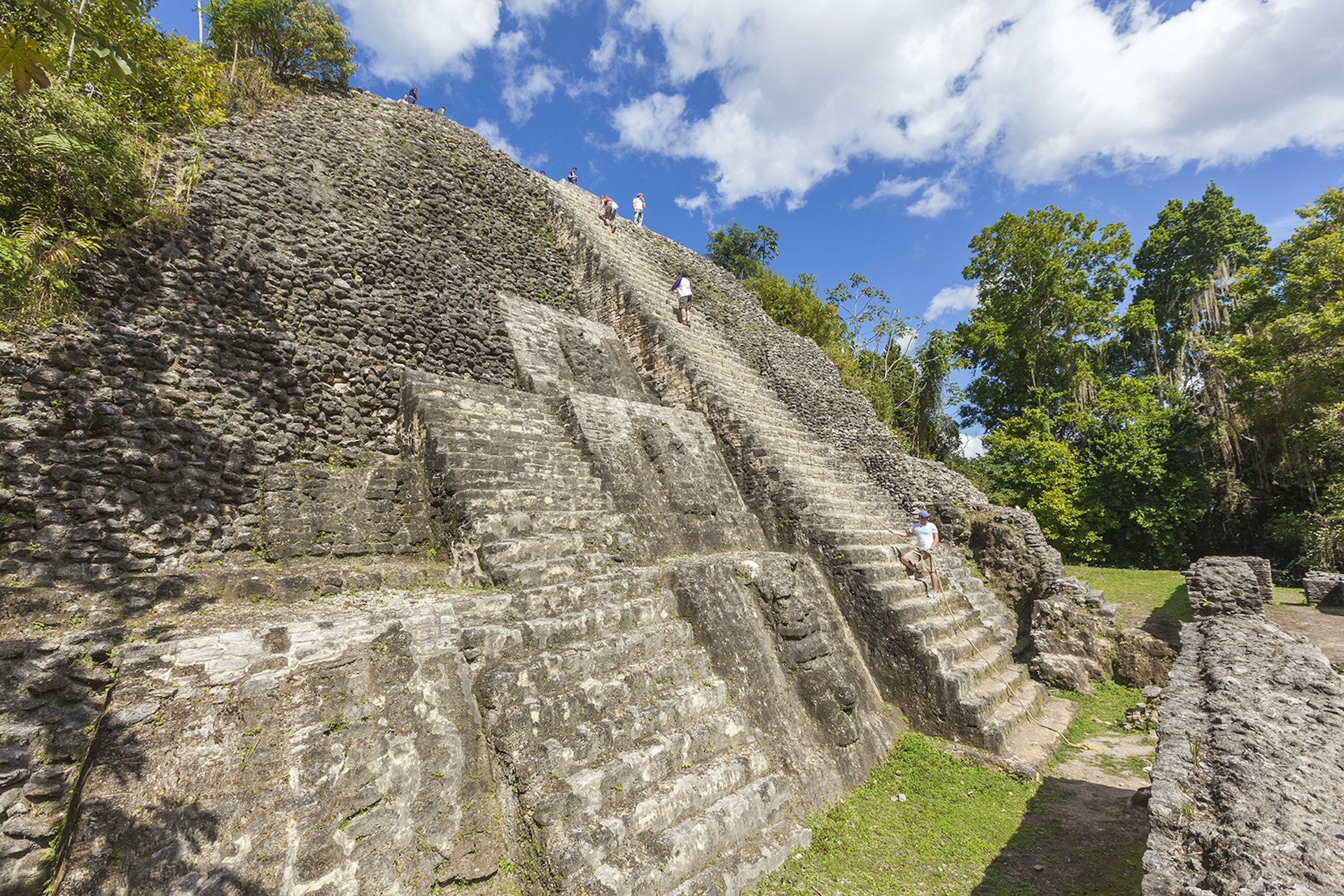 Visitors climb to the top of the Maya ruins in Lamanai, Belize © Patrick J Endres - AlaskaPhotoGraphics / Getty Images