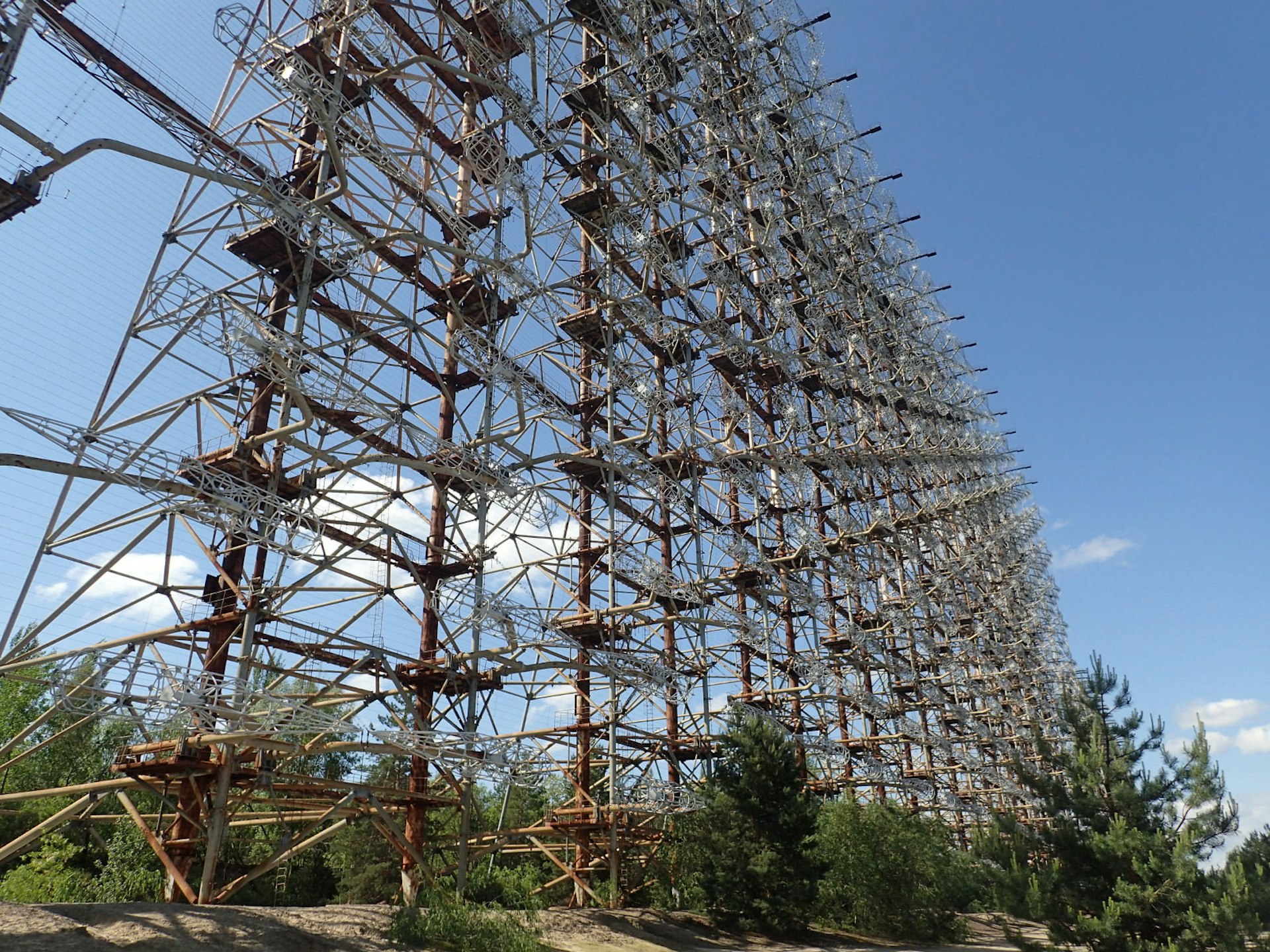 Abandoned radar installation in the Chornobyl Exclusion Zone, resembling a huge scaffolding unit made of lots of grey pipes and brown pillars.