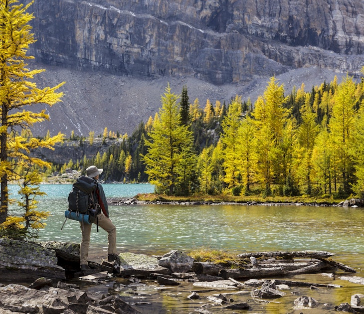 Features - A back packer pauses on the shore of Skoki Lake in the Skoki wilderness area of Banff National Park, Alberta, Canada. Model Released