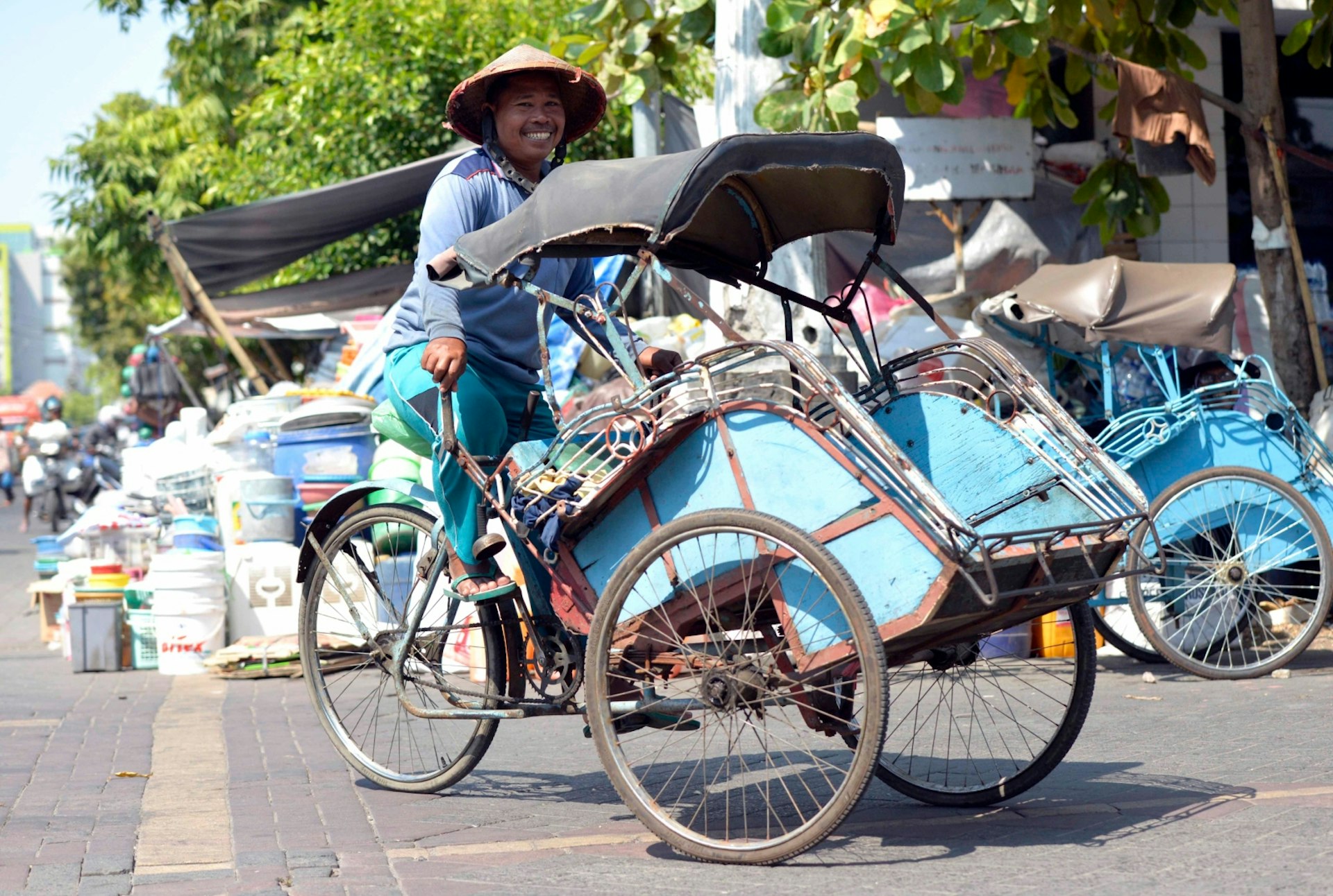 A trishaw driver smiles for a photo in Semarang, Central Java, Indonesia © Mark Eveleigh / Lonely Planet