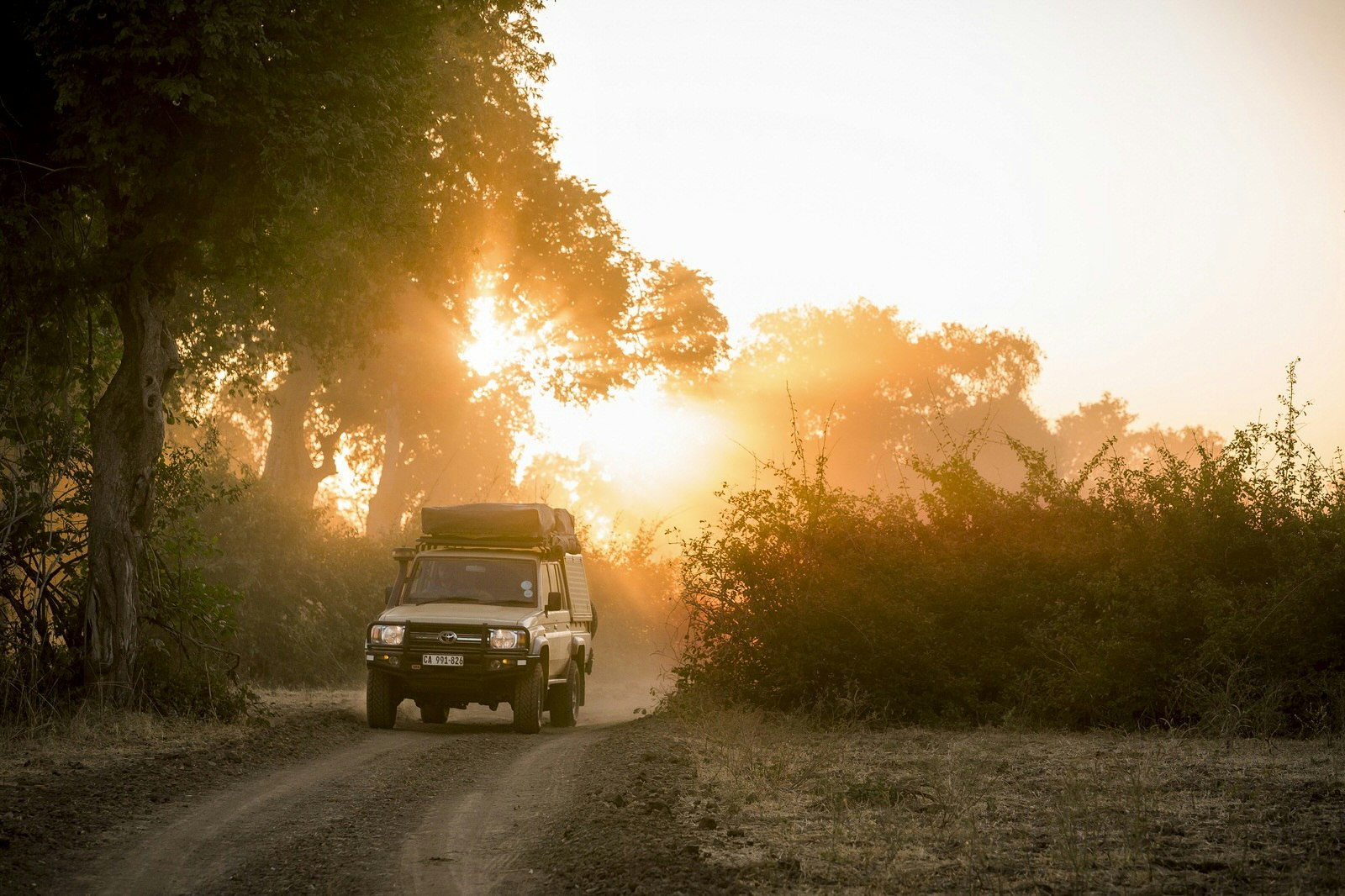 A Land Cruiser drives along bush tracks to South Luangwa National Park, Zambia © Philip Lee Harvey