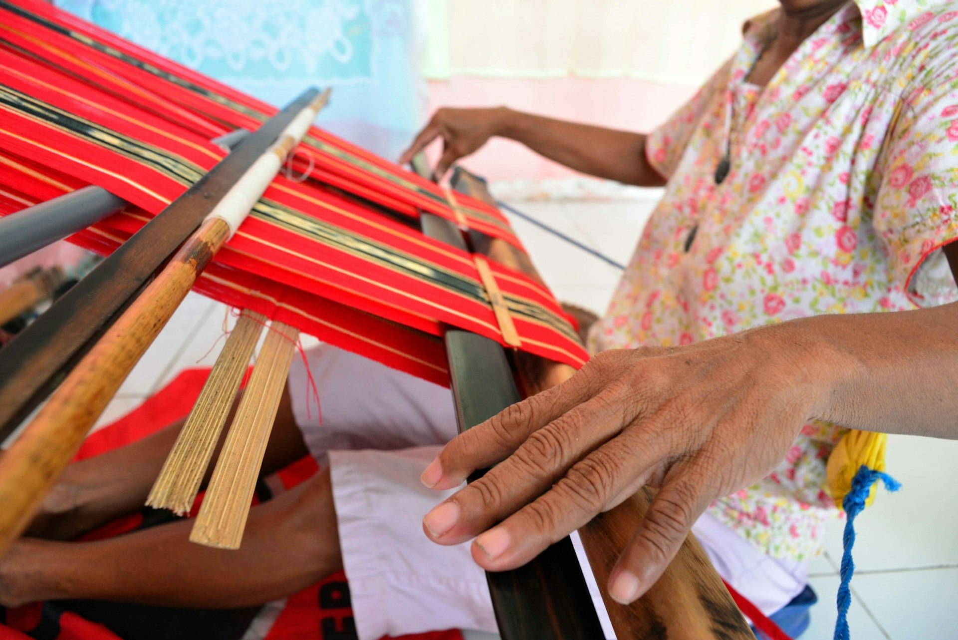 An Indonesian woman hand-weaves textiles © Mark Eveleigh / Lonely Planet