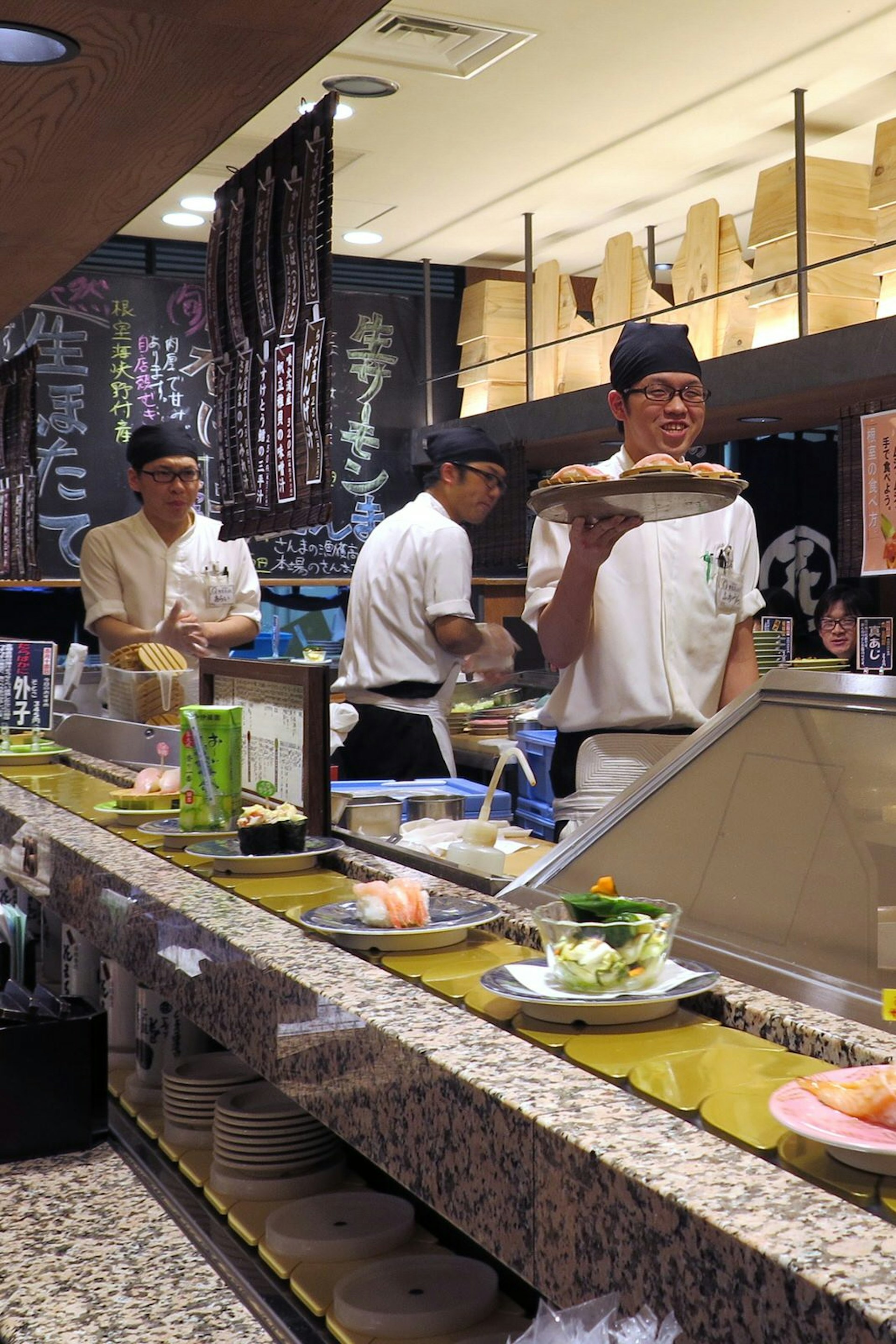 Chefs working behind the counter as plates of sushi pass by on the conveyor belt