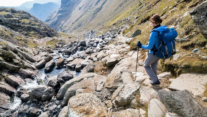 A hiker descends Stickle Ghyll, a steep trail offering views of waterfalls and lakes, in Great Langdale © Duncan Andison / Shutterstock