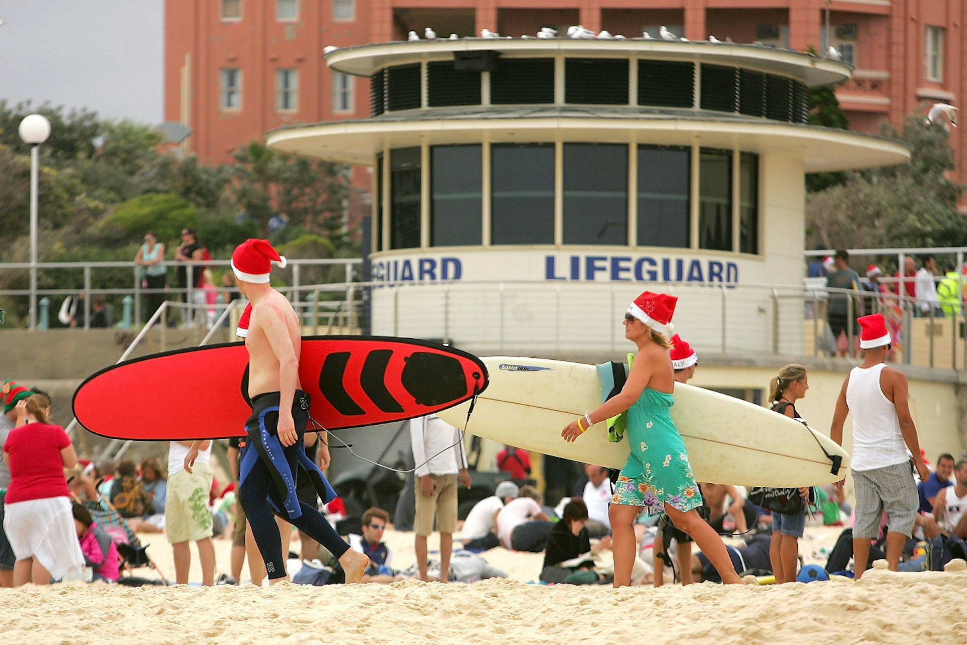 SYDNEY, AUSTRALIA - DECEMBER 25: Surfers wear Santa hats as walk down Bondi Beach on December 25, 2007 in Sydney, Australia. Bondi Beach is a popular destination for tourists on Christmas Day. (Photo by Ezra Shaw/Getty Images)