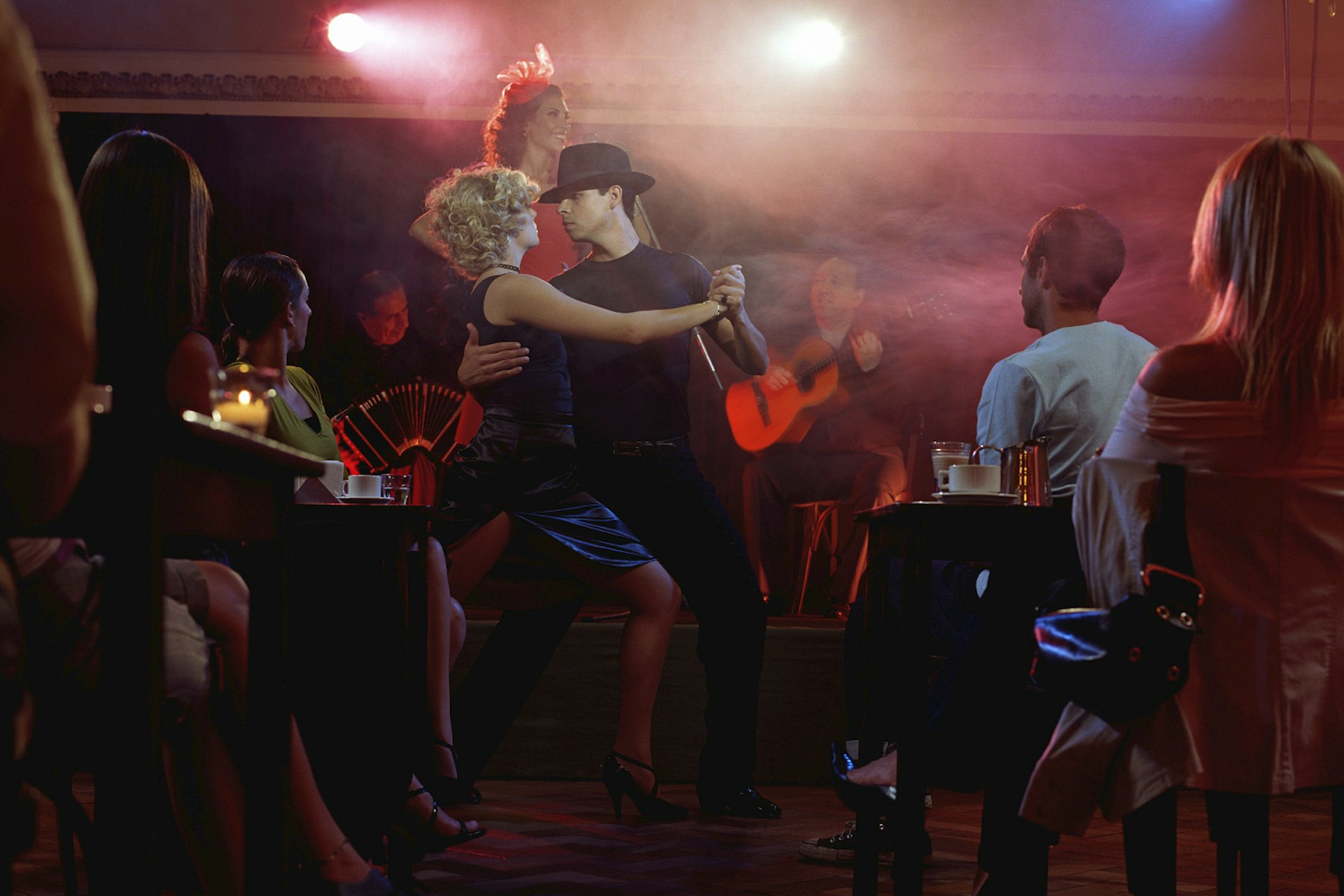 Young couple dancing tango for audience in restaurant