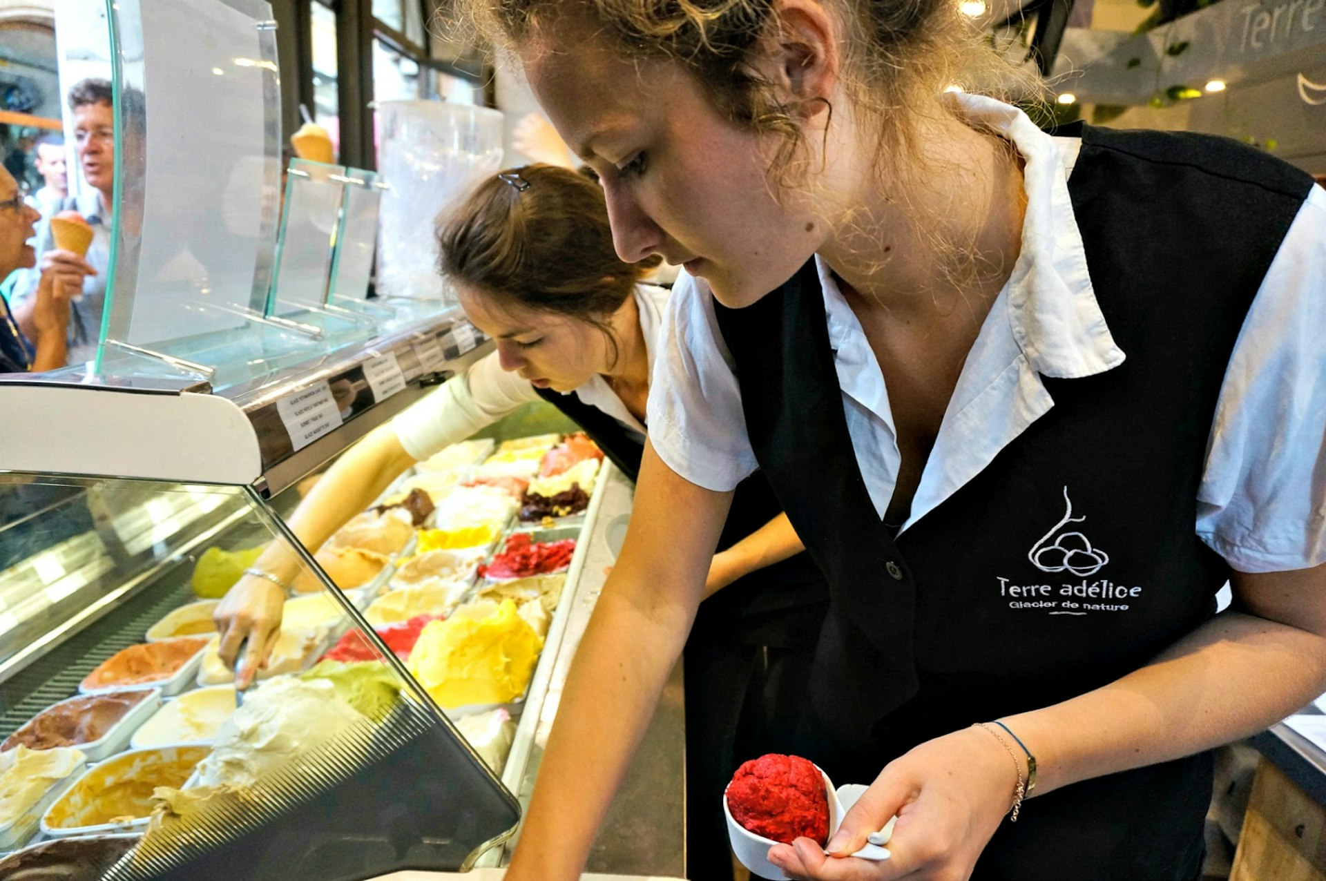 Assistants serving up scoops at Terre Adélice. Image © Monica Suma / Lonely Planet