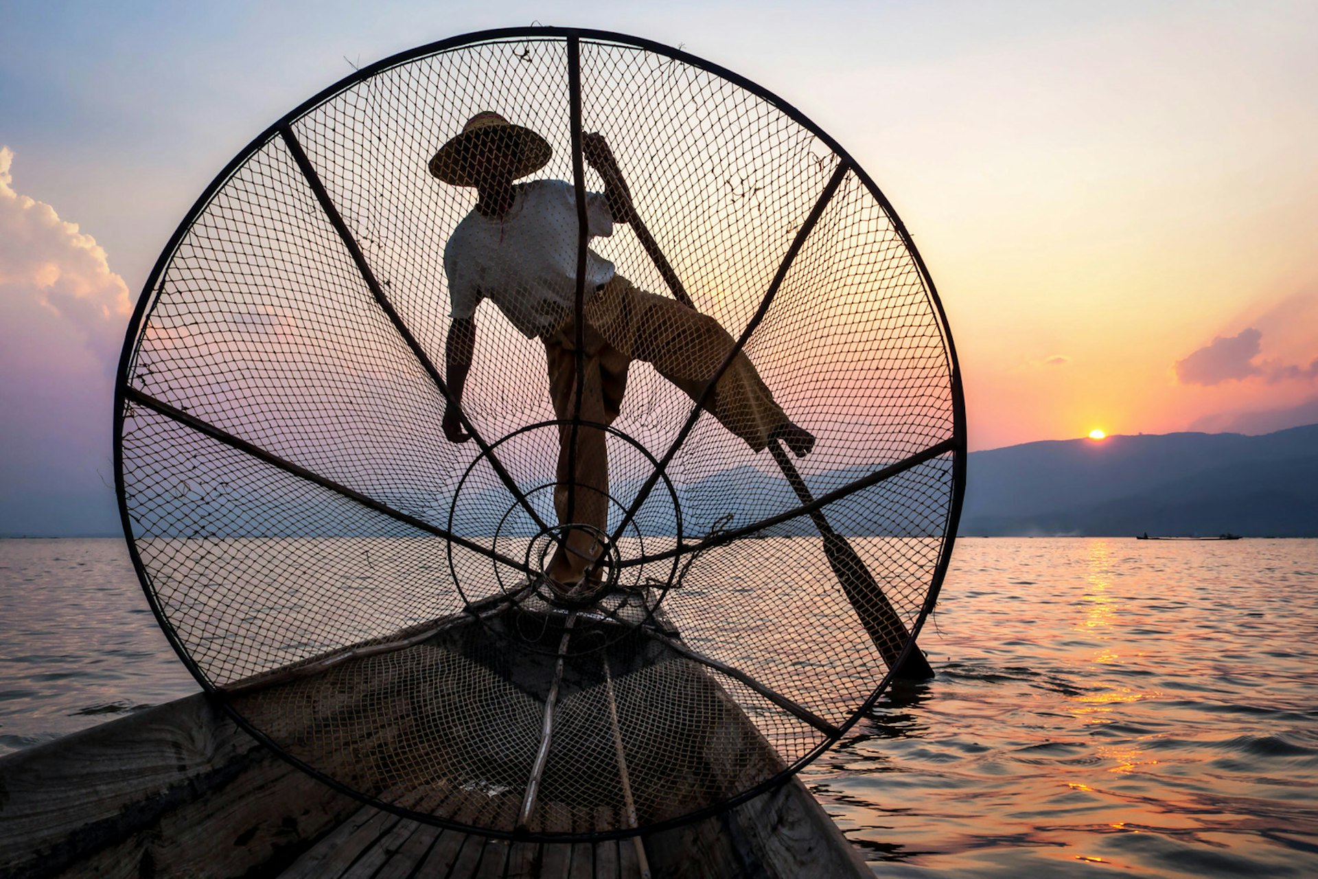 An Intha fisherman rowing at sunset 