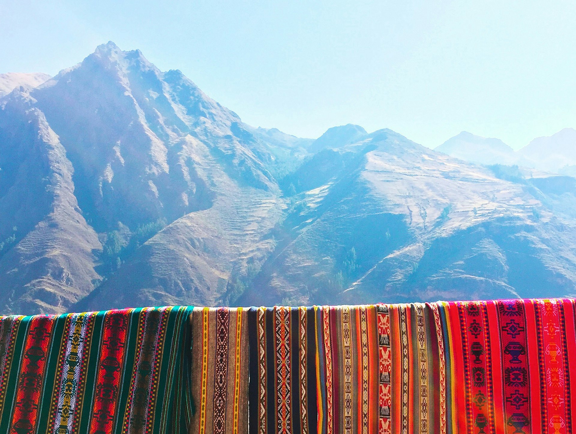 Handwoven tapestries hanging over the rail of a Sacred Valley mountain overlook is a simple but striking way to frame Peru's Andean Peaks using the rule of thirds © MaSovaida Morgan / Lonely Planet