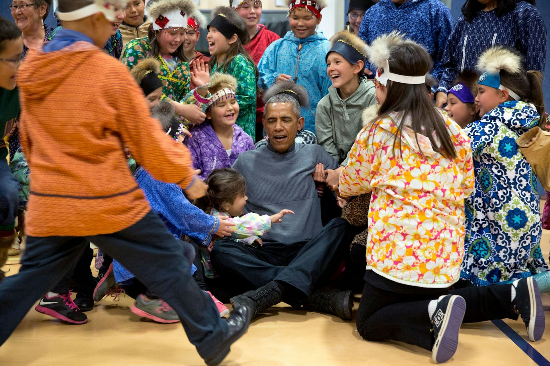 The president being helped to his feet after a group photo with the performers at Dillingham Middle School, Alaska © Pete Souza / Official White House Photo