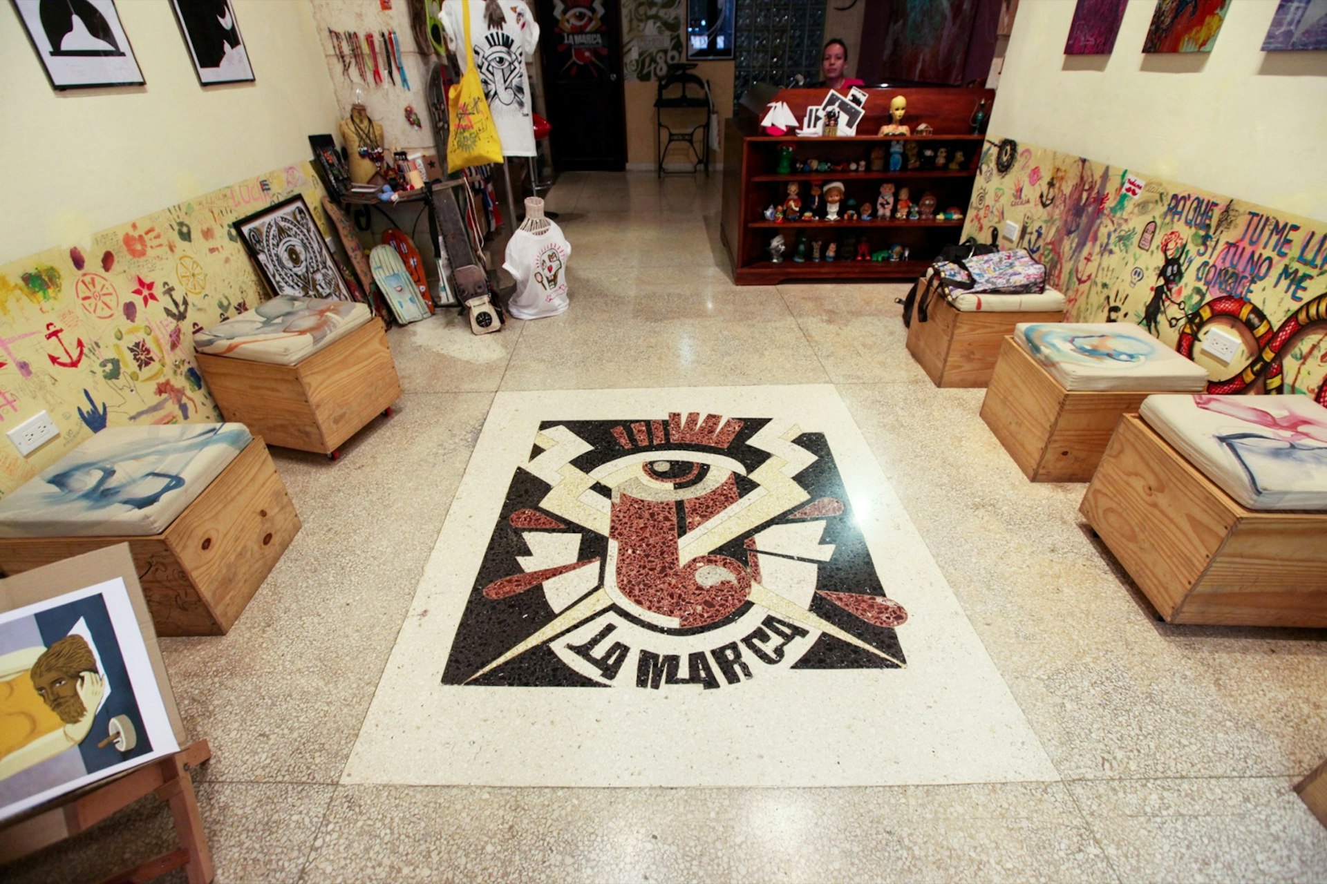 A large La Marca logo is embossed on the title floor. It's surrounded with wooden chairs and a large desk in the back. The wall is filled with framed pictures on the wall; shopping doesn't just include clothing in Havana 