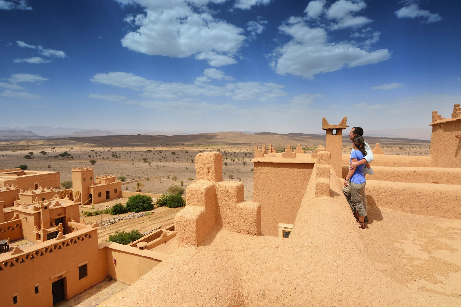 Young couple in a kasbah looking out at a view of a sand-colored city