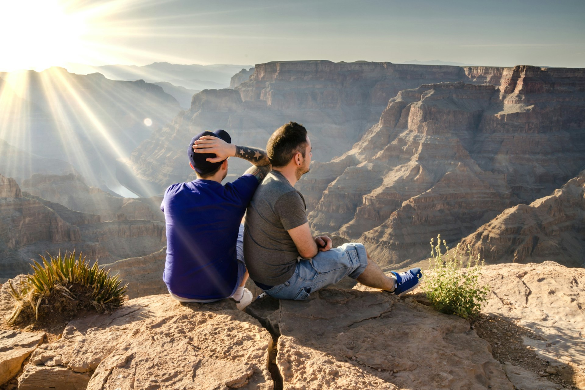 A couple sit looking out over a beautiful canyon.