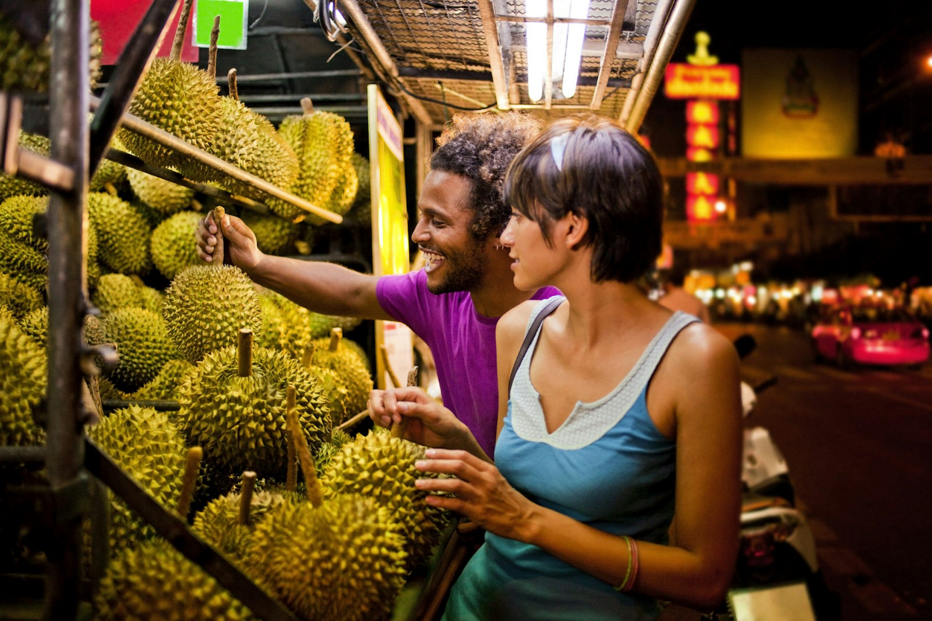 A couple examine fruit at a stall 
