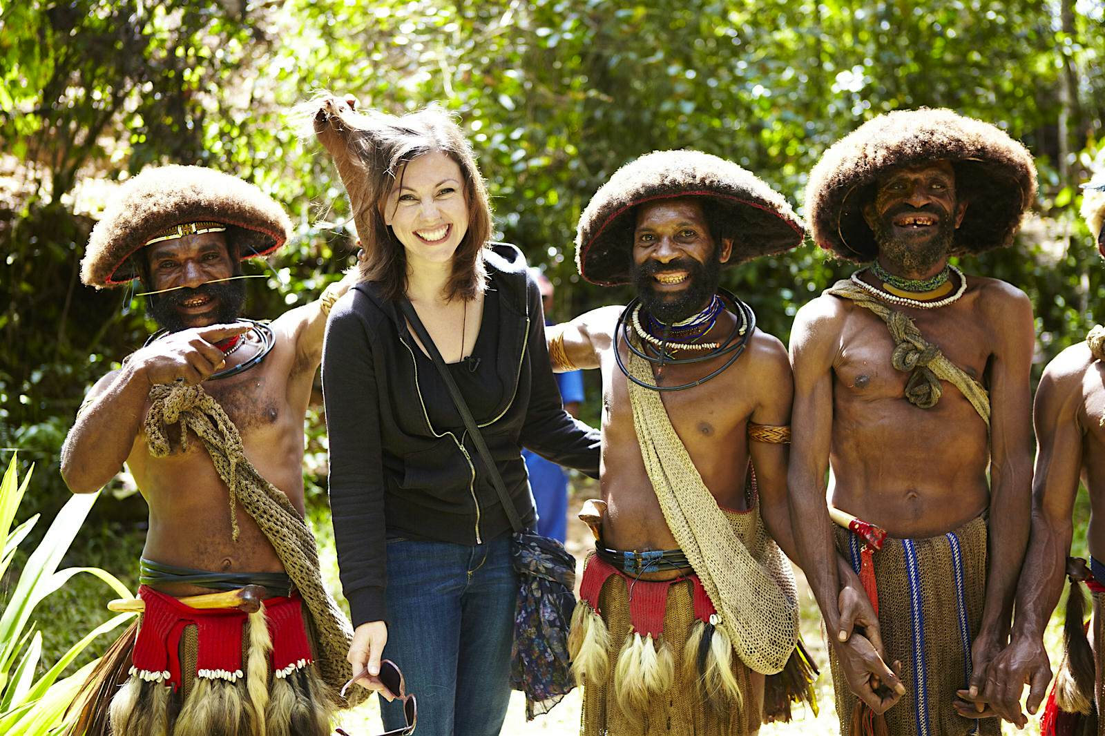 Features - Christa with three Huli Wigmen in Tari region. A woman poses for a photo with a trio of Huli Wigmen in the Tari region.