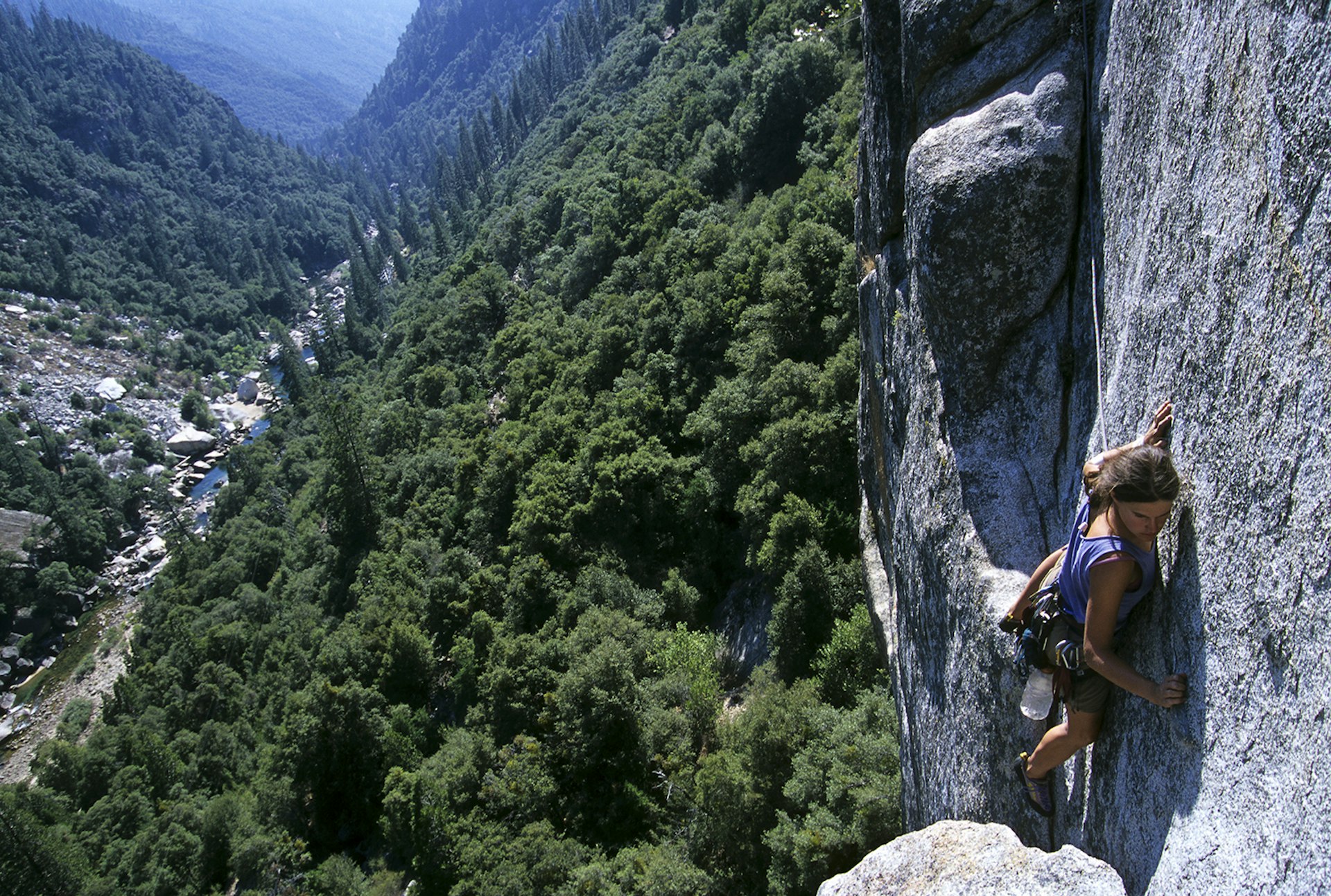 Features - Woman rock climbing high above river