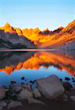 The irresistible mountain lake at Refugio Frey in the Argentine Andes at sunset. The still blue water reflects the jagged orange peaks that are bathed in the suns warm light.