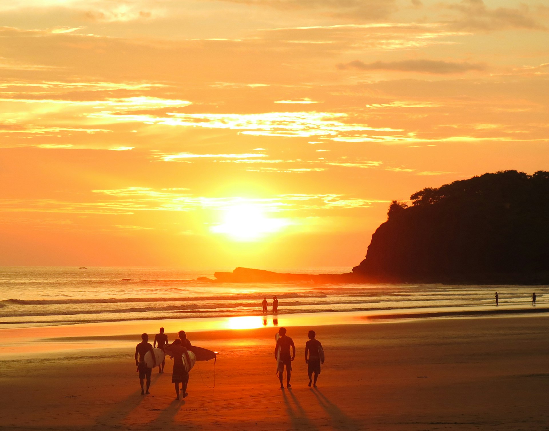 Features - Surfers and beach goers gaze at the golden orange sunset