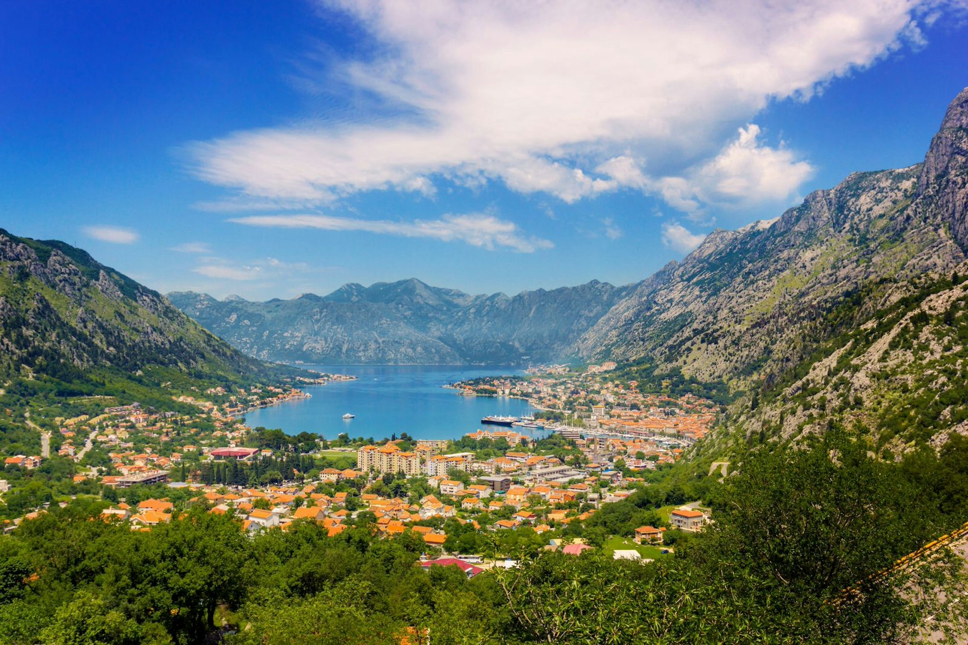 The dramatic Bay of Kotor: a blue inlet is surrounded by the orange roofs of Kotor Town with the whole scene fenced in by jagged rocky peaks.