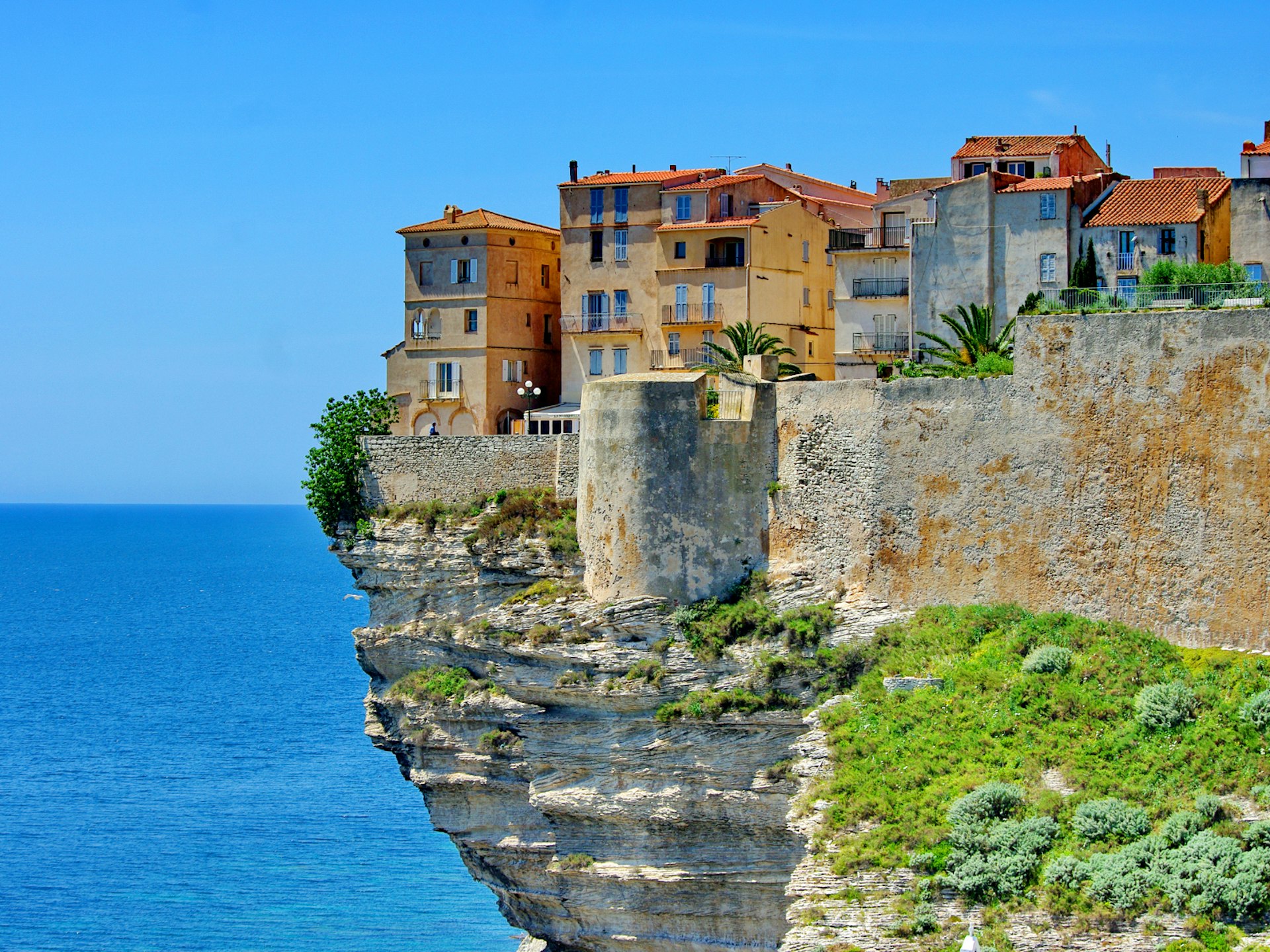 A cliff with several tall houses on top juts out over the sea
