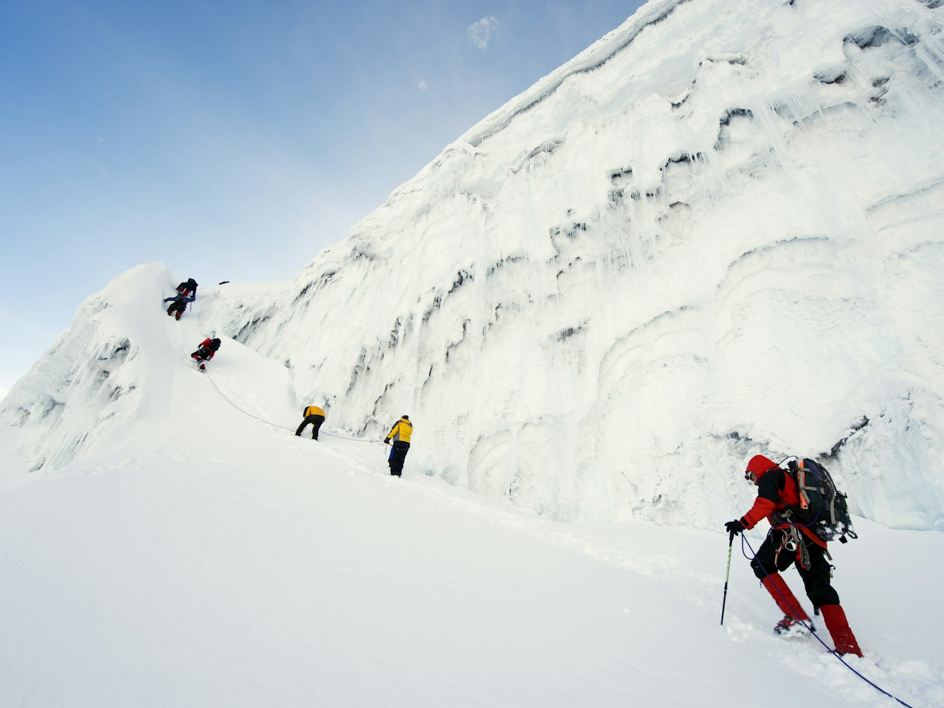 Five climbers laden with mountain-climbing gear work their way up a snowy path on the slopes of Volcan Cotpaxi