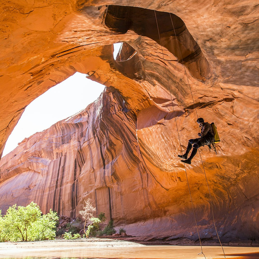 Features - A man rapelling while canyoneering in a desert canyon.