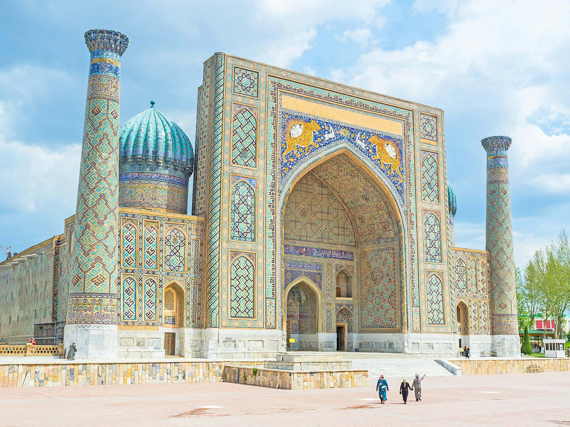Minarets flank the square entrance to this building, which is covered in tiles of turquoise, blue and yellow. There's a turquoise dome at the back