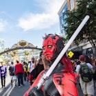 woman dressed as a black red Darth Maul Sith with her light saber under the Gas Lamp sign
