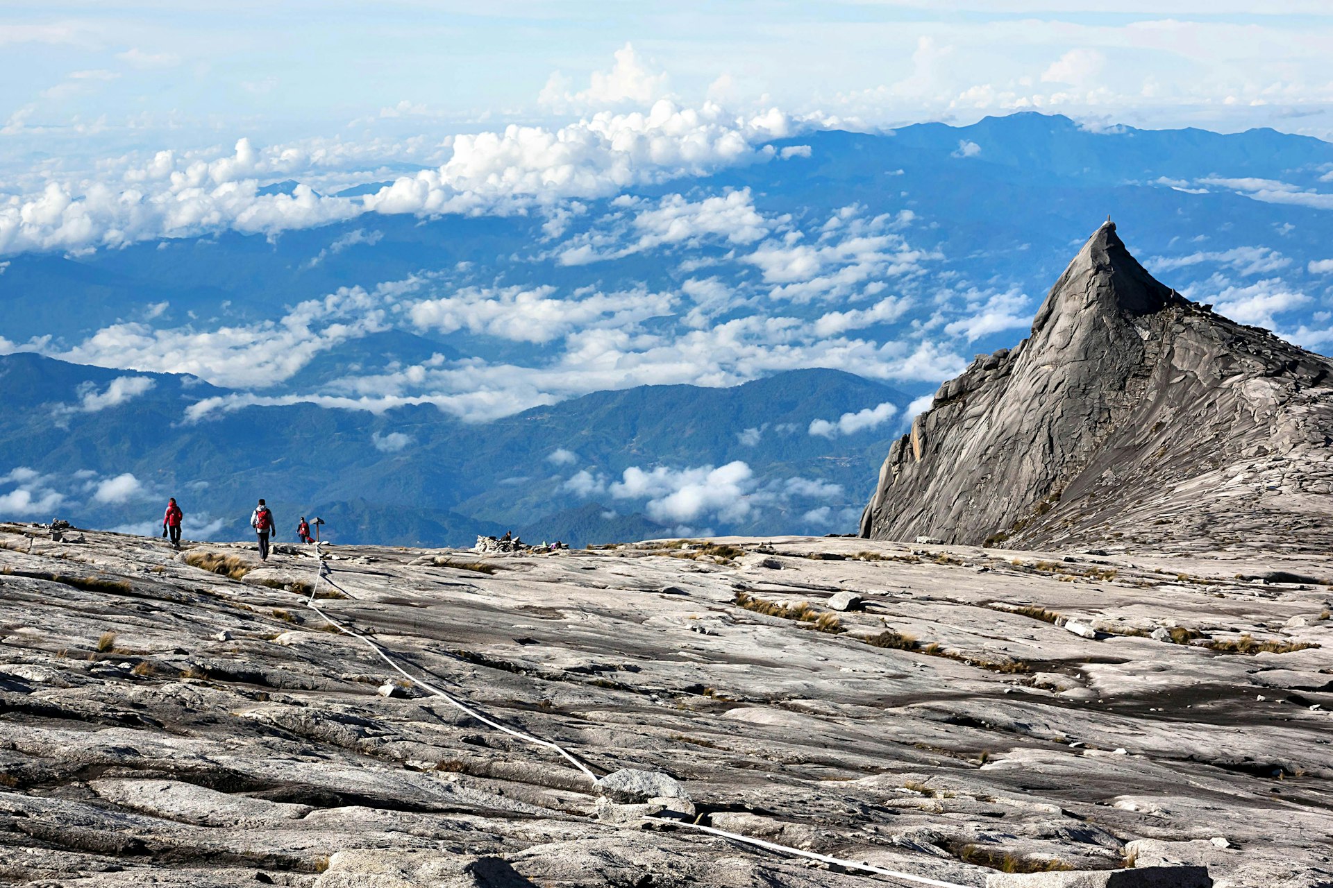 The summit of Mount Kinabalu, with jagged rock formations and a spectacular view over cloud-covered peaks