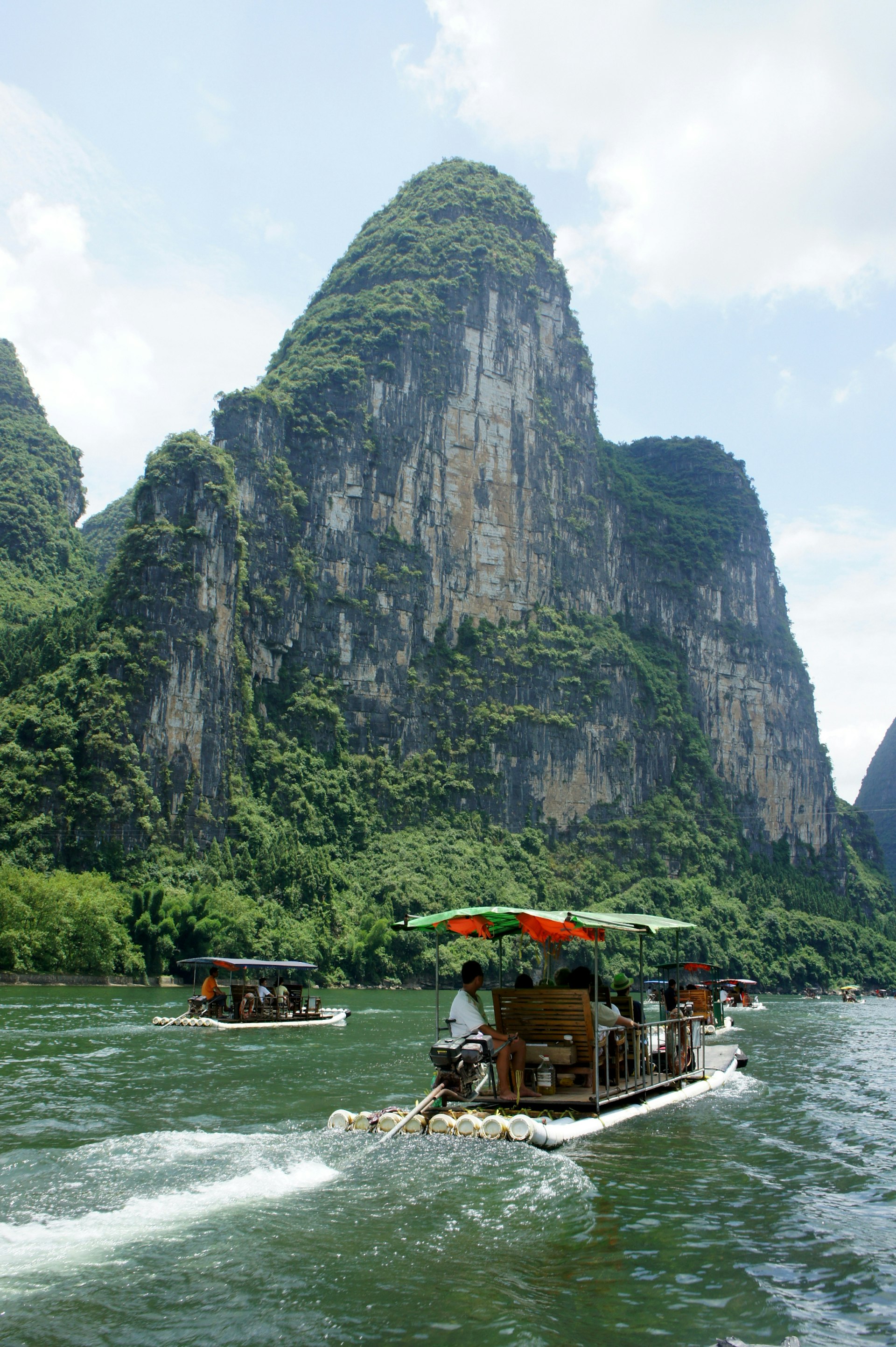 Two boats on the Li River, Guilin, with a large rocky feature looming over the river