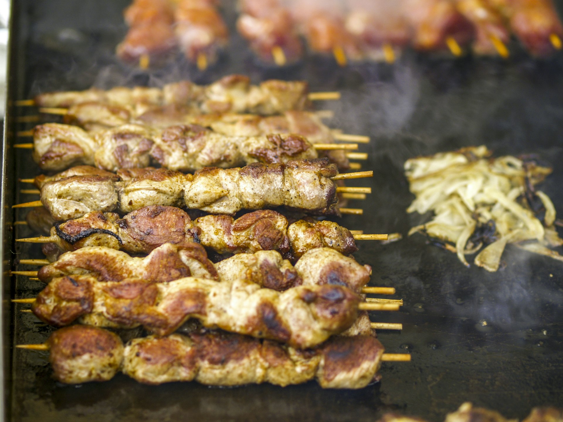 Kebabs sizzle on a griddle at Vienna's Naschmarkt