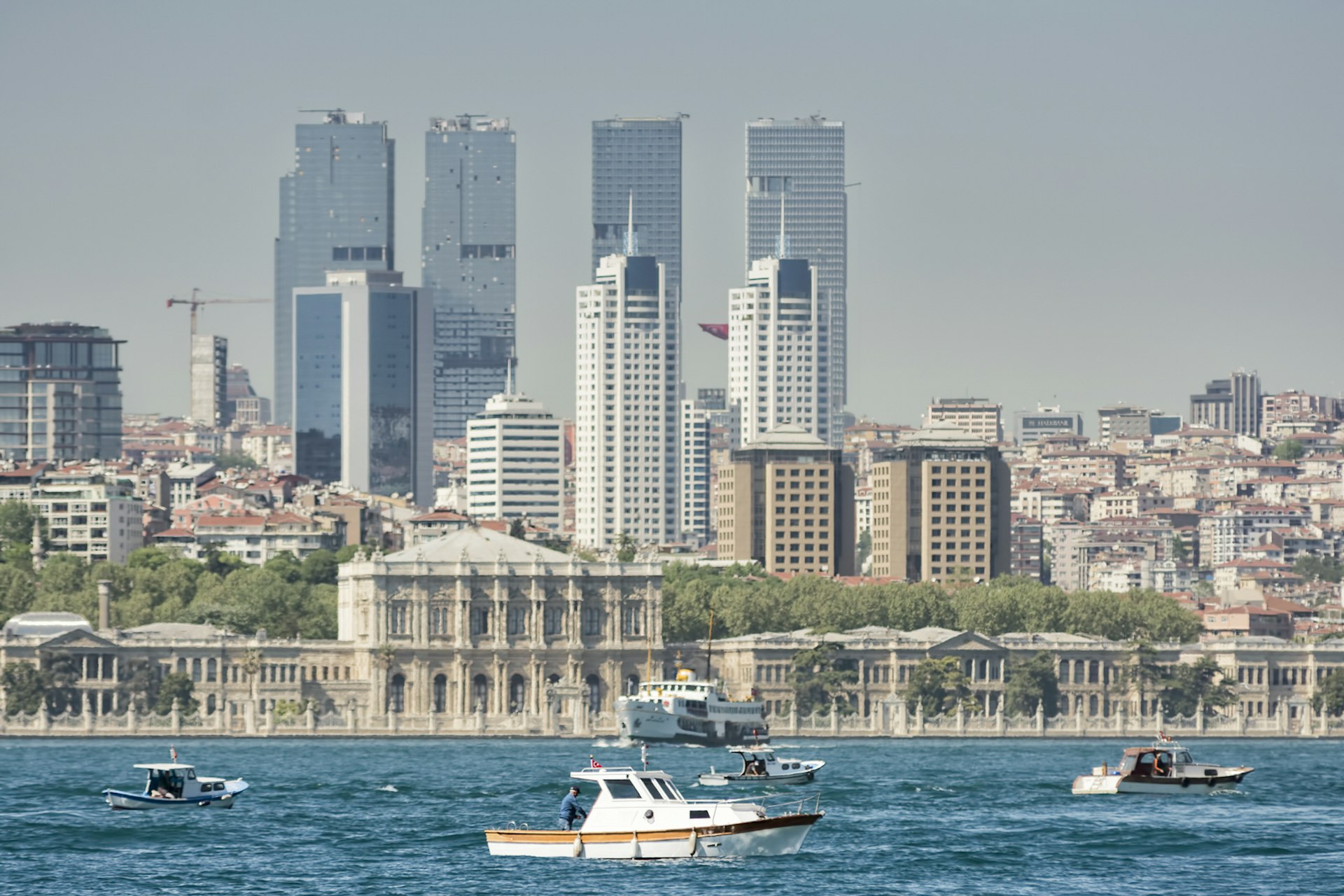 Fishing boats on the Bosphorus, Dolmabahce Palace and skyscrapers from Besiktas District in the background, Istanbul, Turkey