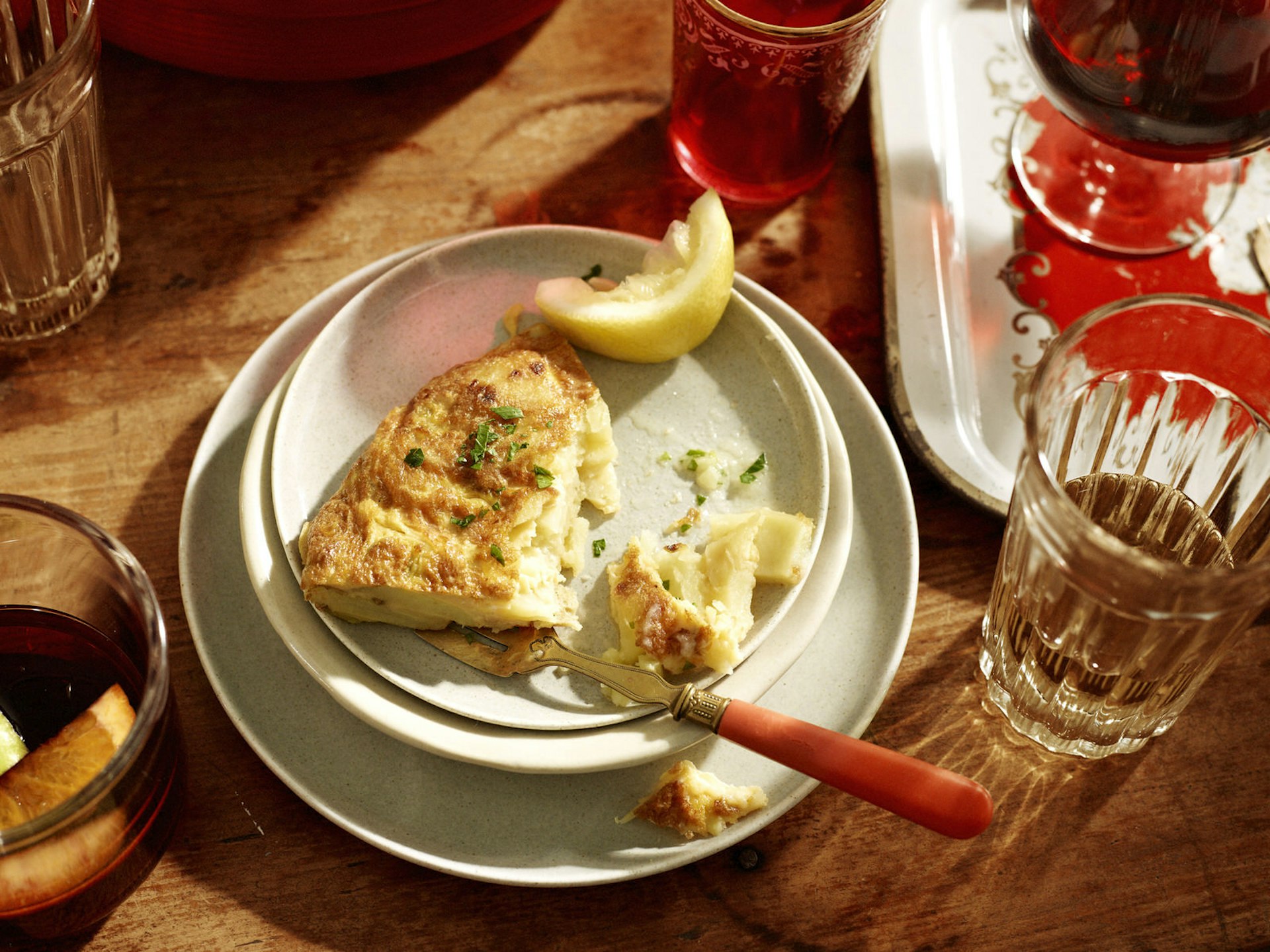 A Spanish omelette (tortilla) sits half eaten on a plate, accompanied by a glass of sangria © BRETT STEVENS / Getty Images