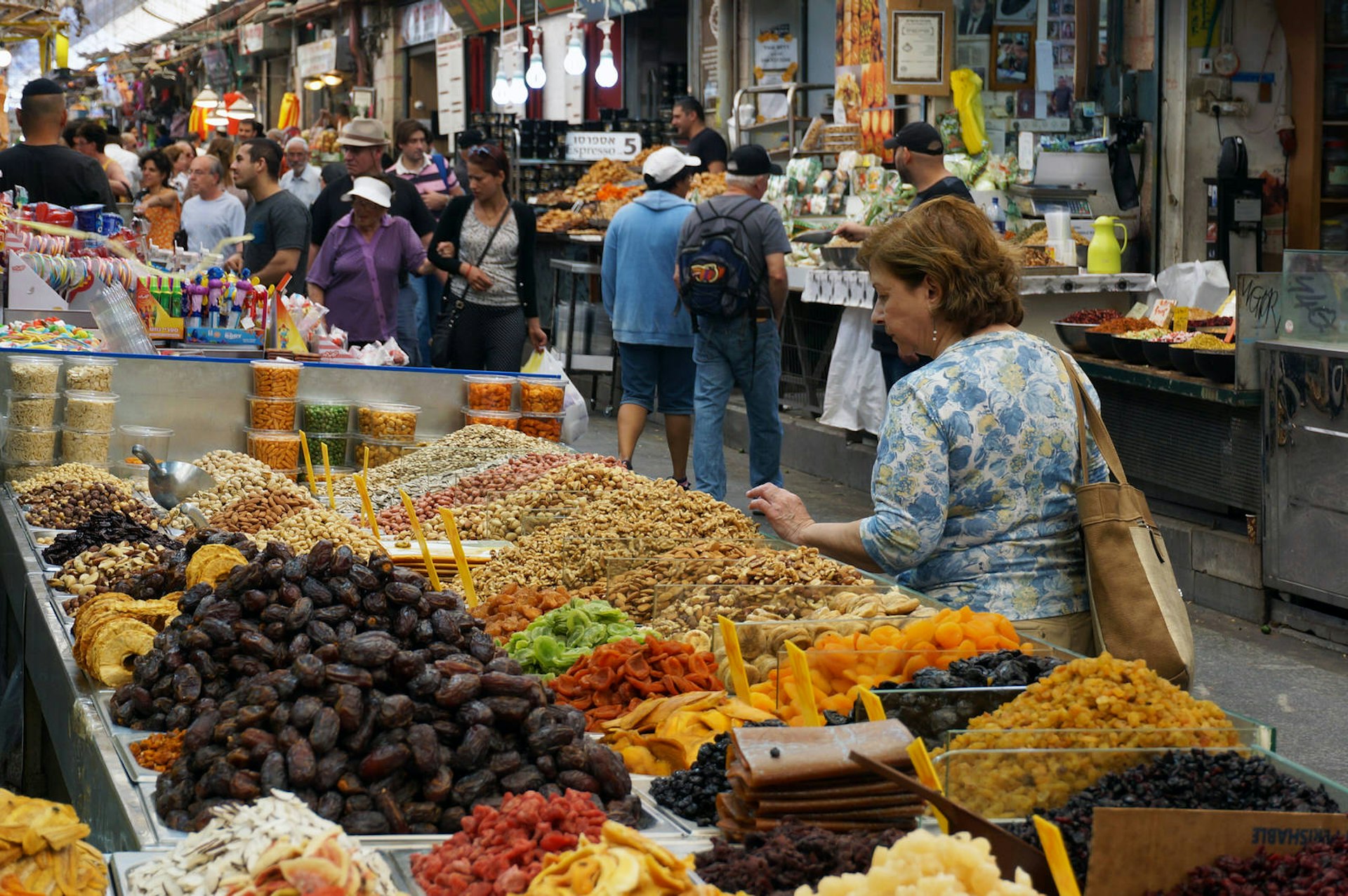 Gluten-free travel: A woman ponders the bounty of dried fruit and nuts at Mahane Yehuda Market in Jerusalem © Anita Isalska / Lonely Planet