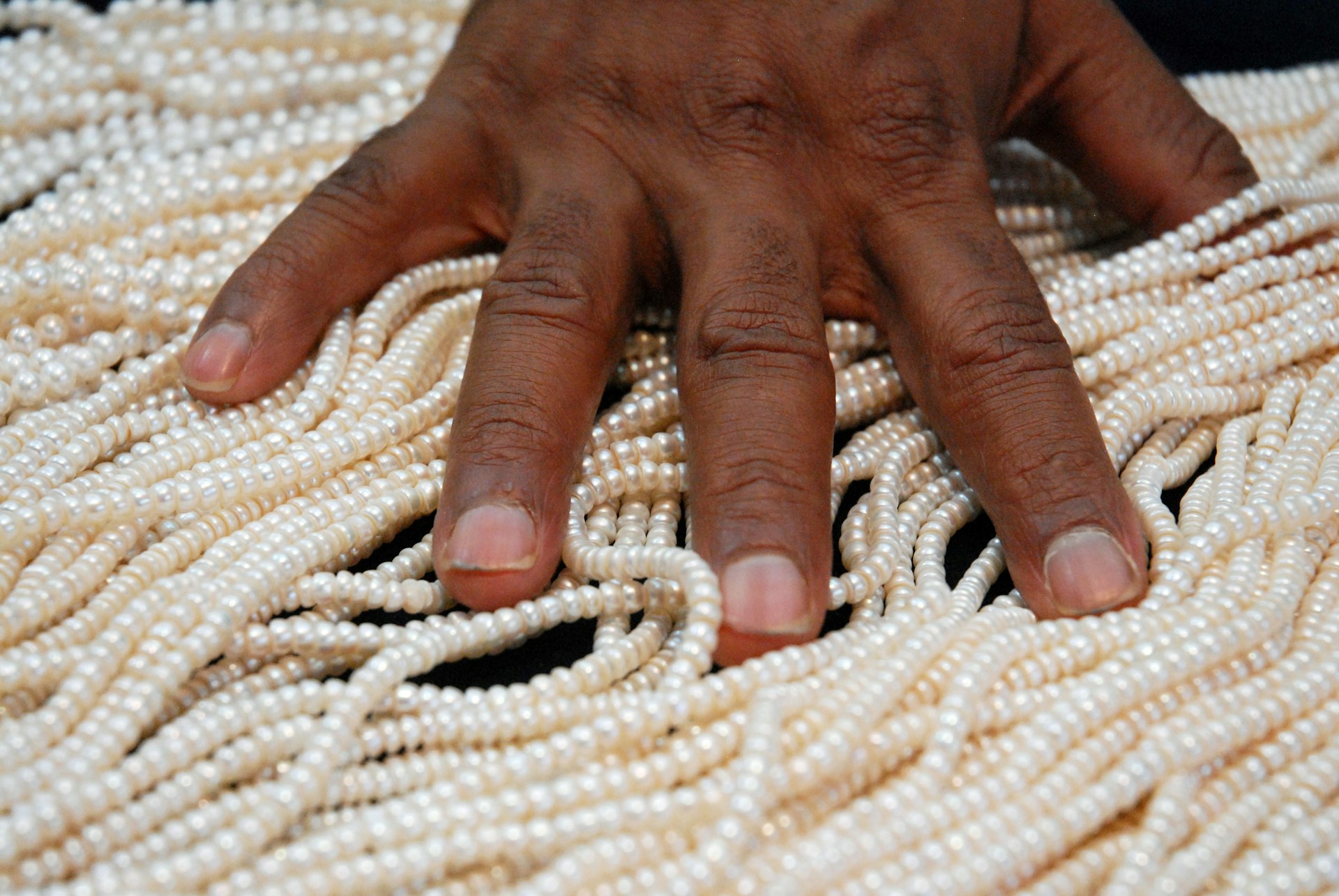 A pearl vendor sorts through strands of Hyderbadi pearls
