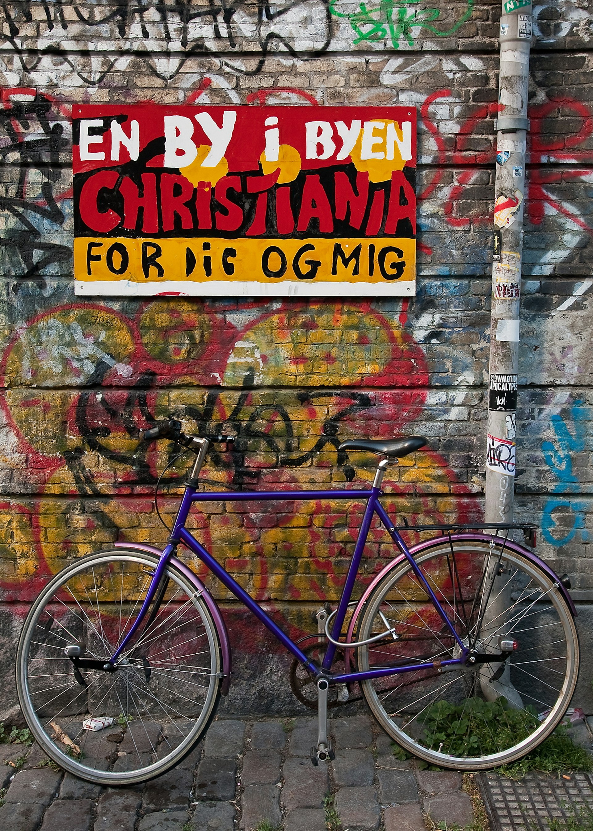 A bike leaning against a graffiti-covered wall in Christiania, Copenhagen, Denmark © Thomas La Mela / Shutterstock