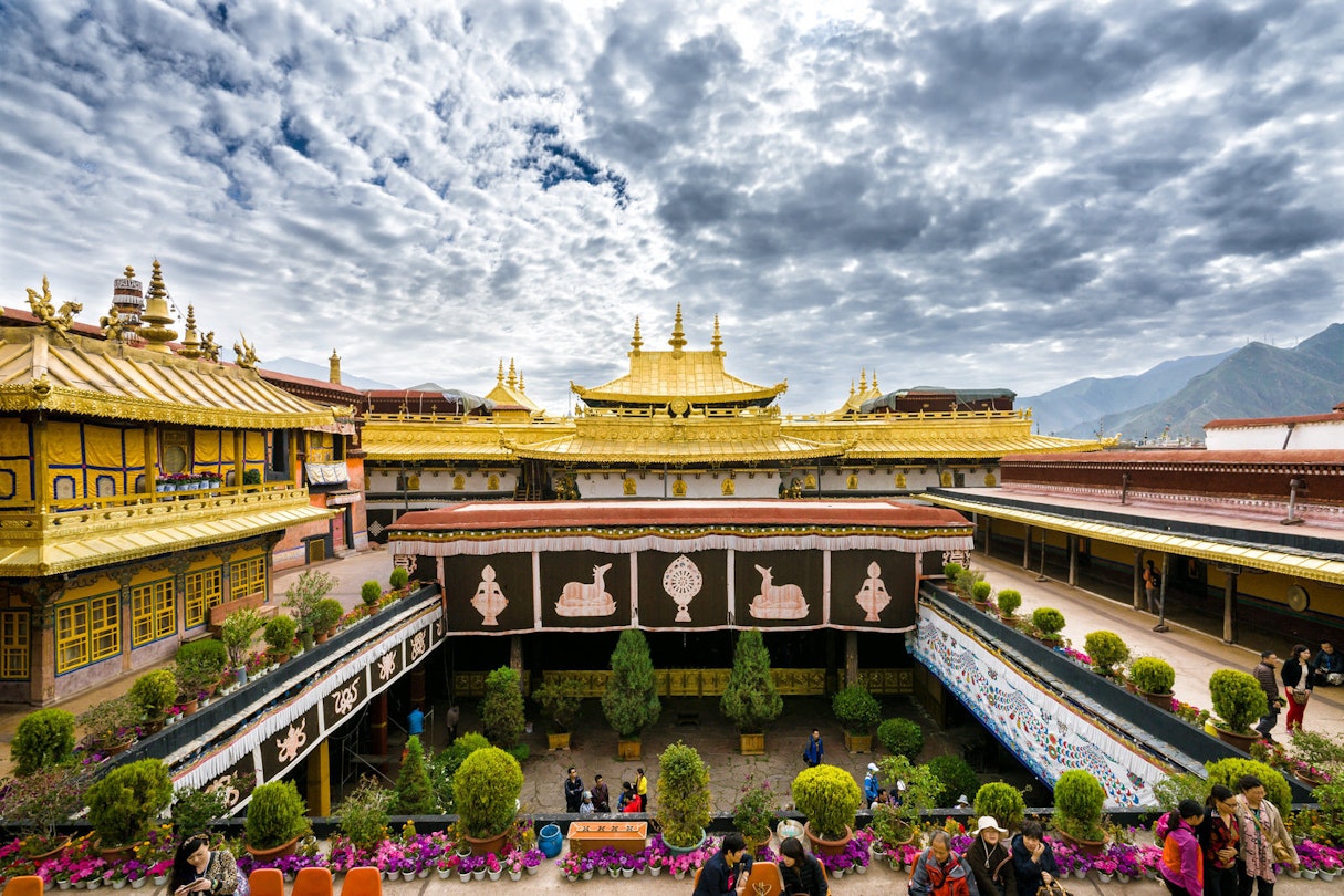 Clouds ripple across the sky above the opulent gold roof of Jokhang Temple, with the courtyard below