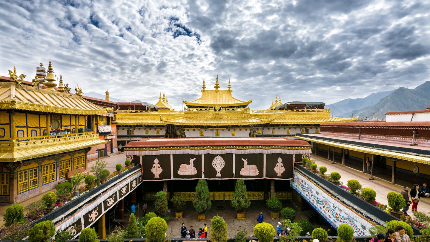 Clouds ripple across the sky above the opulent gold roof of Jokhang Temple, with the courtyard below